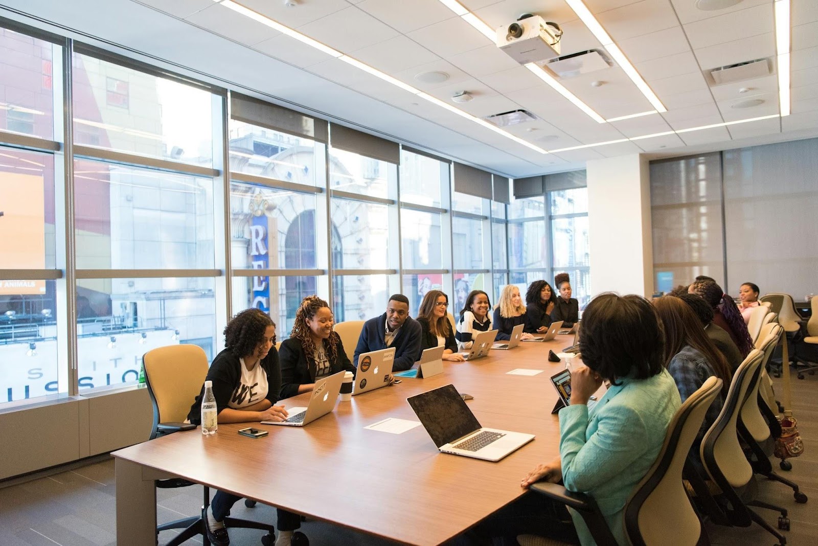 Lots of people sitting around big table in boardroom