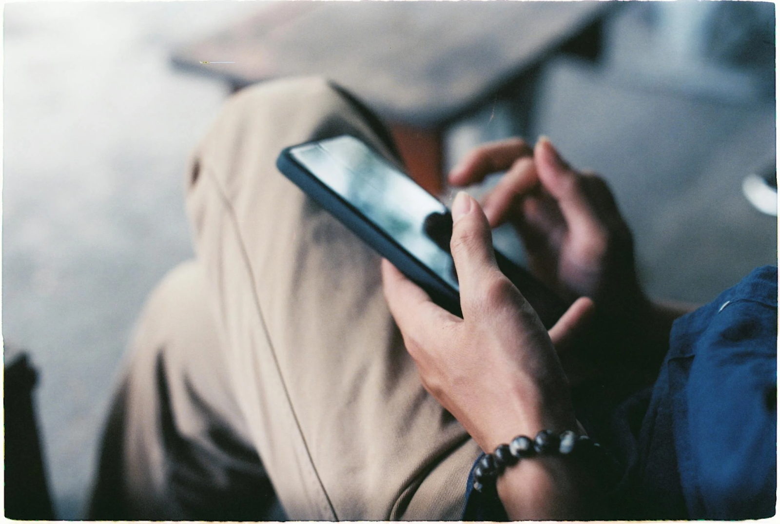 pair of hands holiding mobile phone against crossed legs