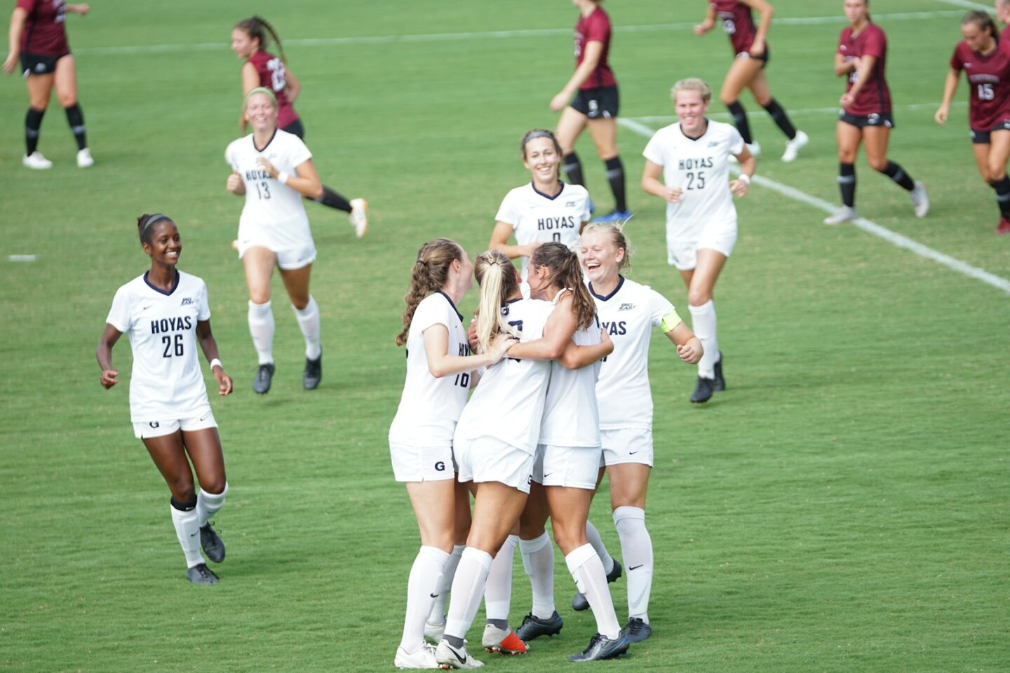women playing football on field and some celebrating in a group