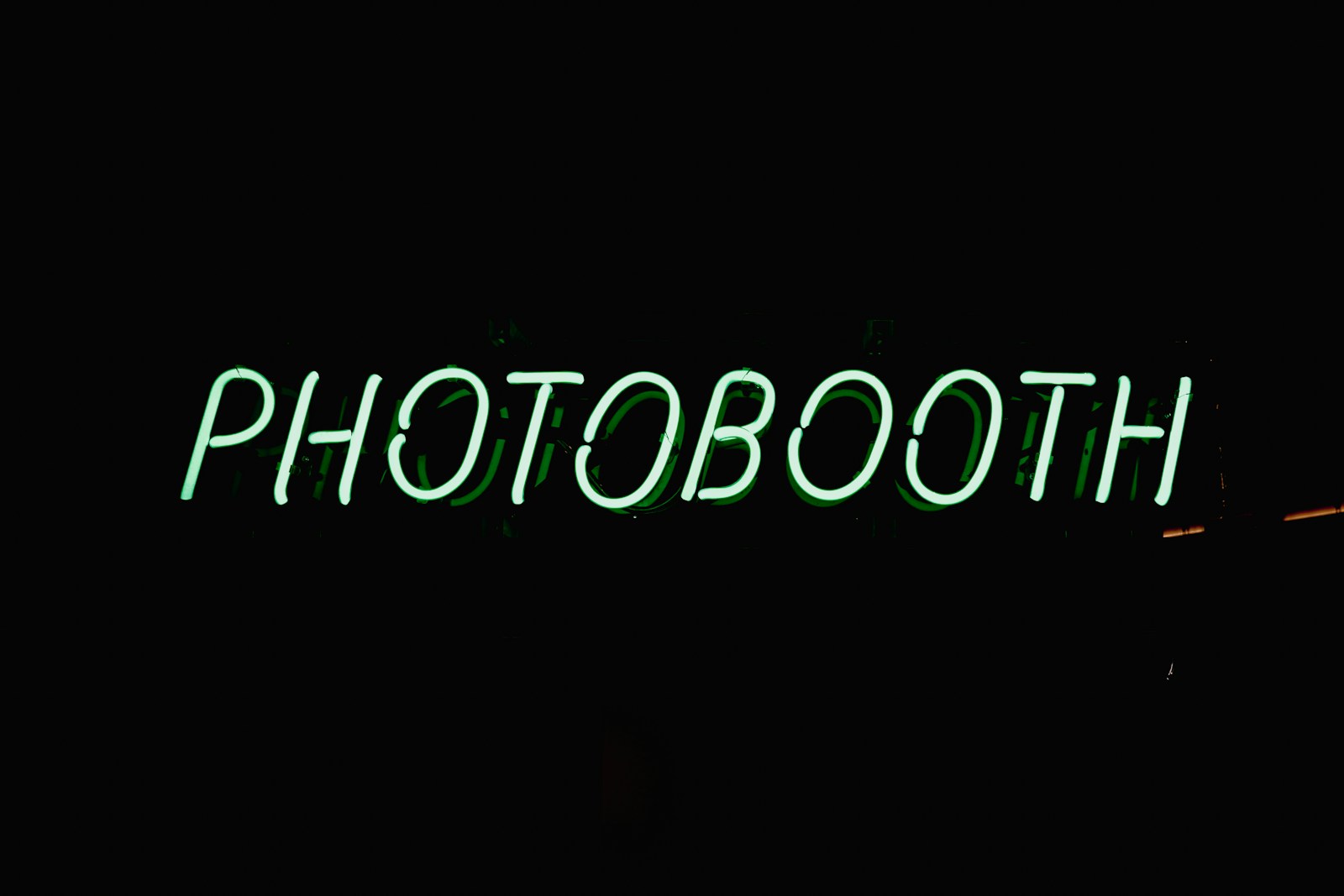 a neon sign that reads photobooth on a dark background