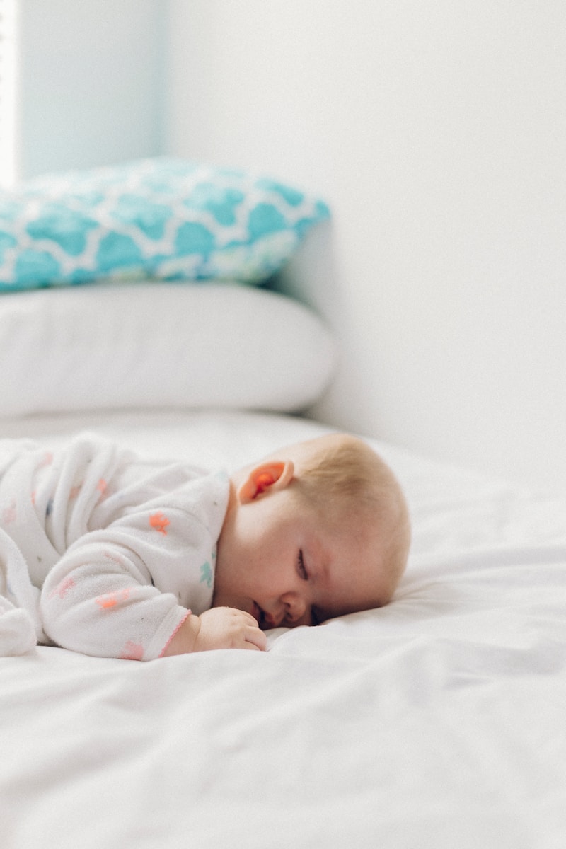 photo of baby laying on their front in bed with no blakets