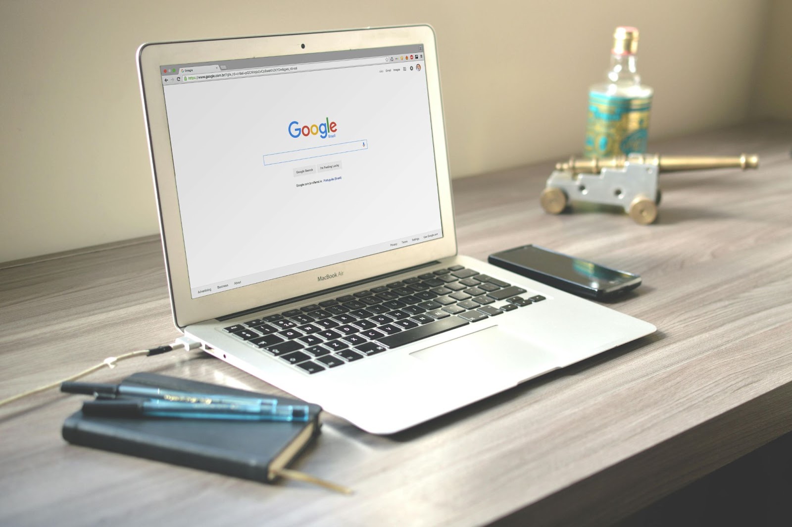 opne laptop with Google on screen on desk with notebook, pen and phone