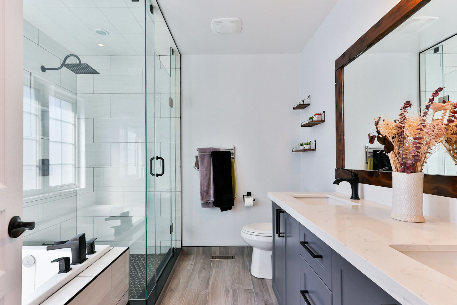 bathroom with big open glass walk-in shower, dark units and wood floor