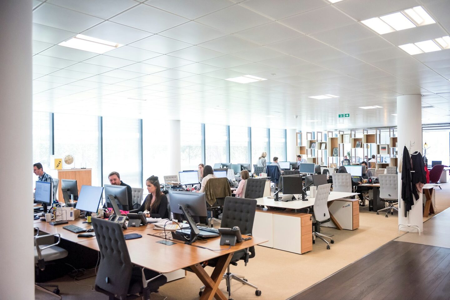 large open office space with lots of people sitting at desks on laptops