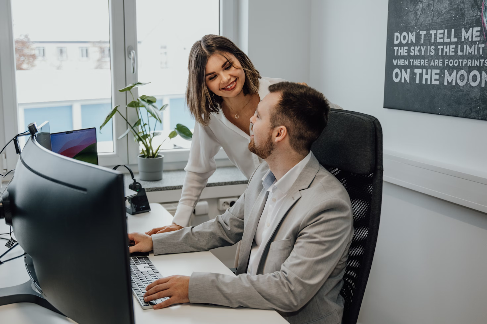 man and woman at work desk smiling at each other
