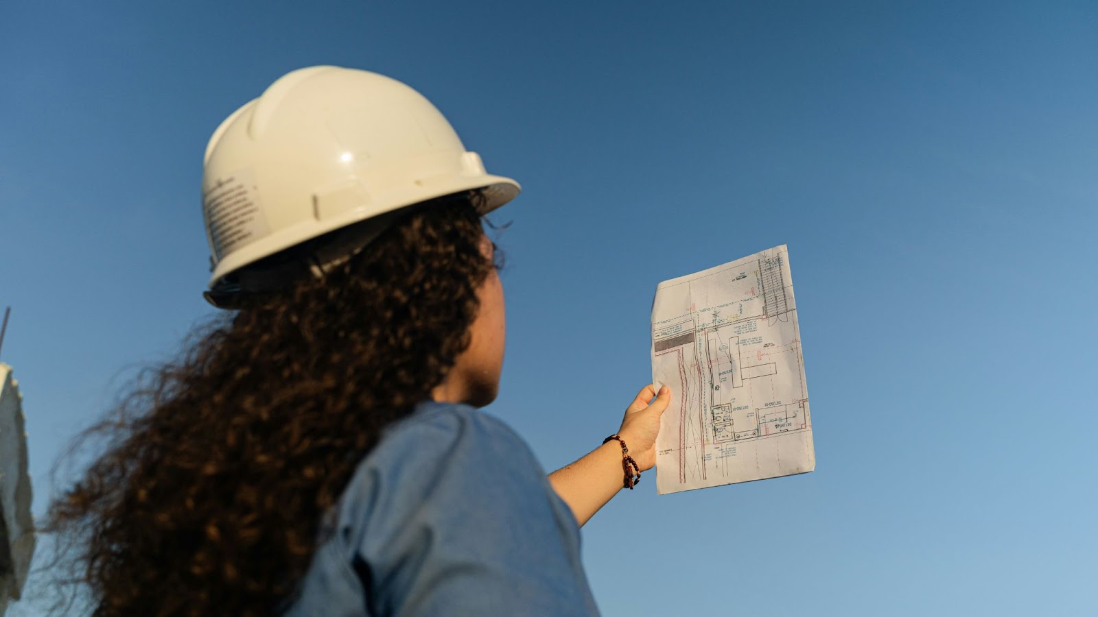 person wearing hat holding layout plans in the air