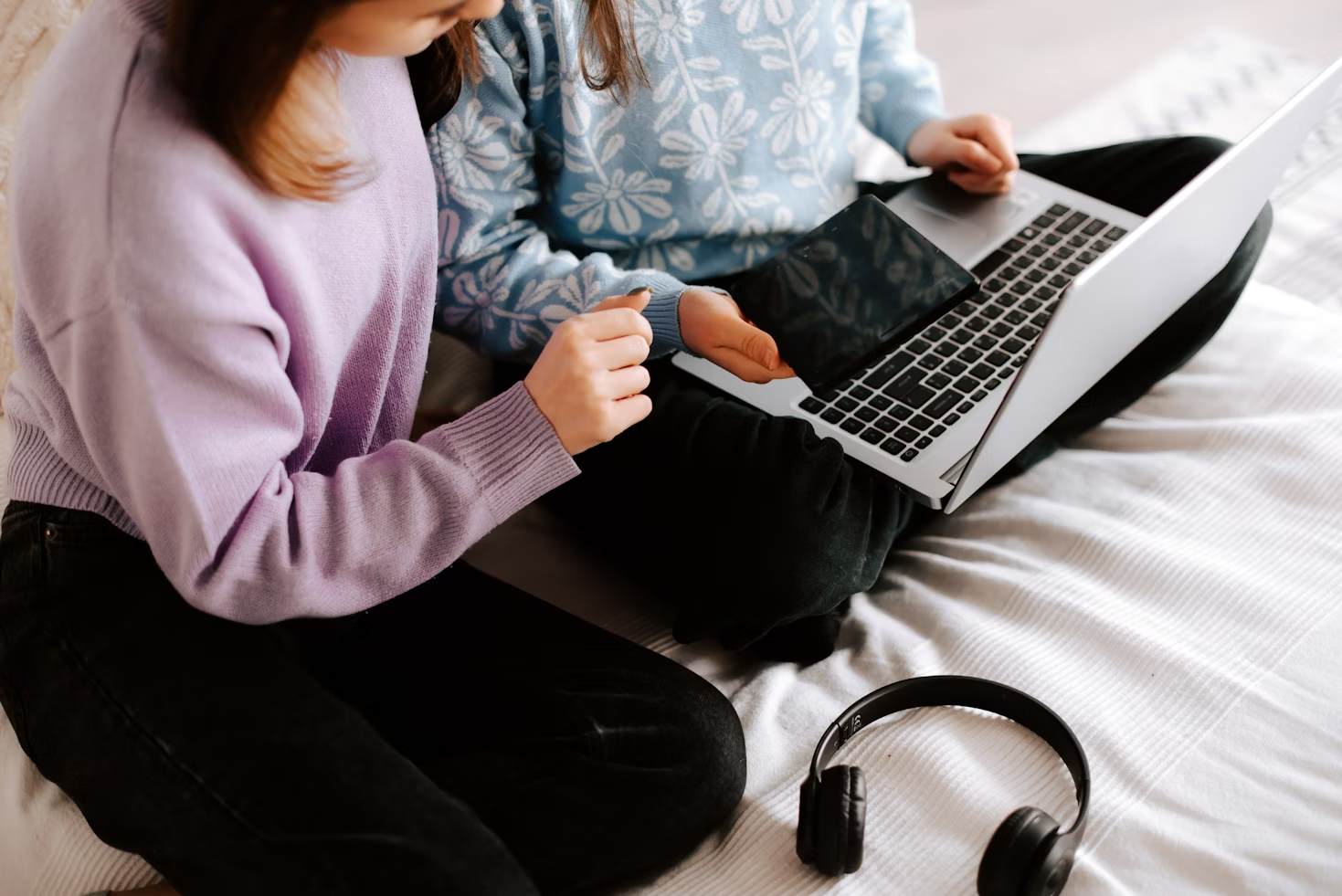 two children sitting on bed on laptop