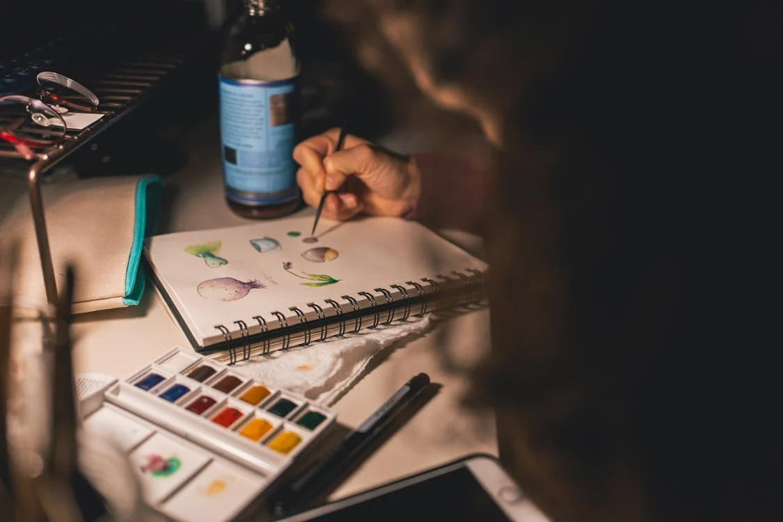 person doing art on sketchpad in low lighting