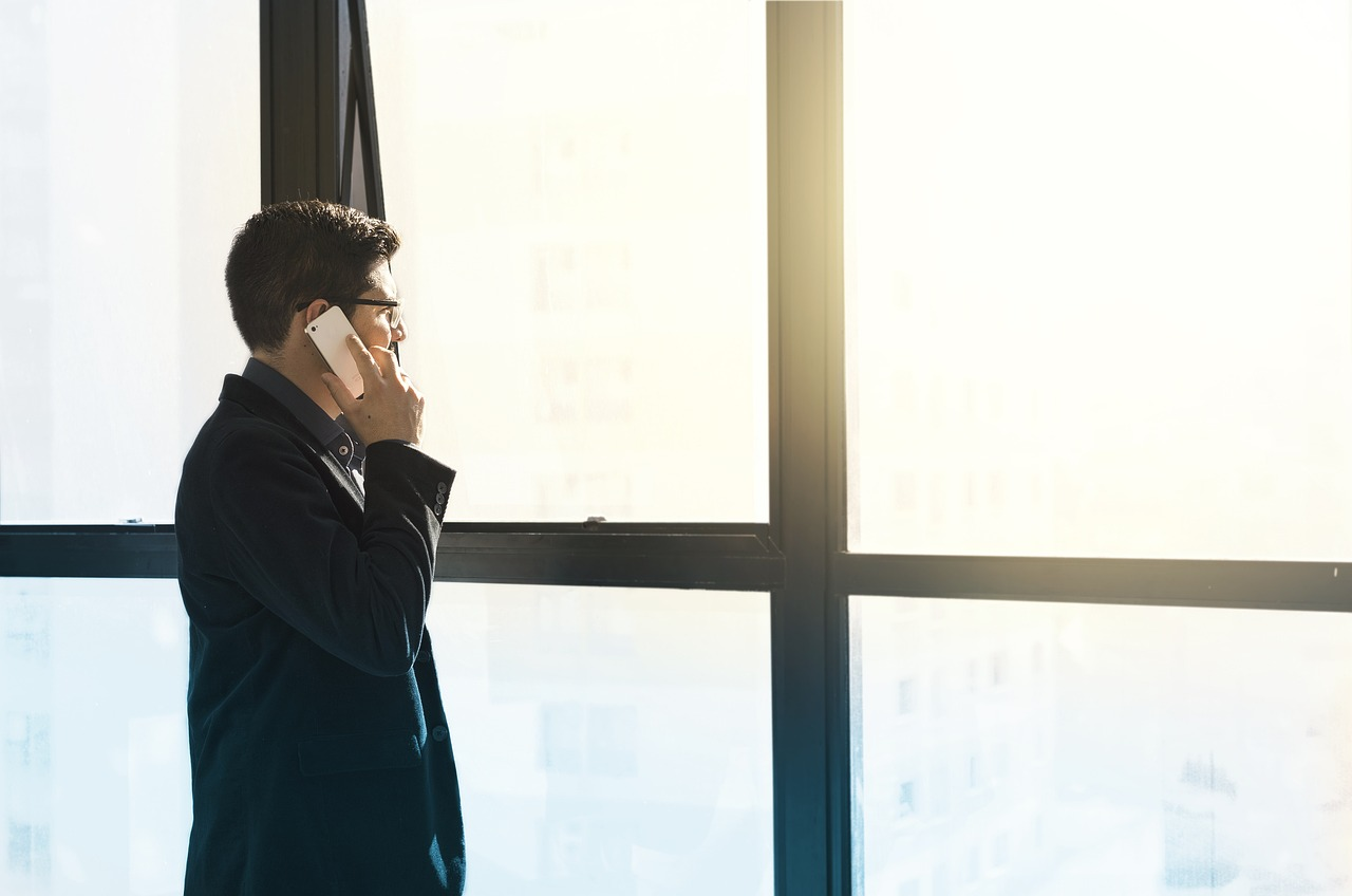 person standing against big window on phone