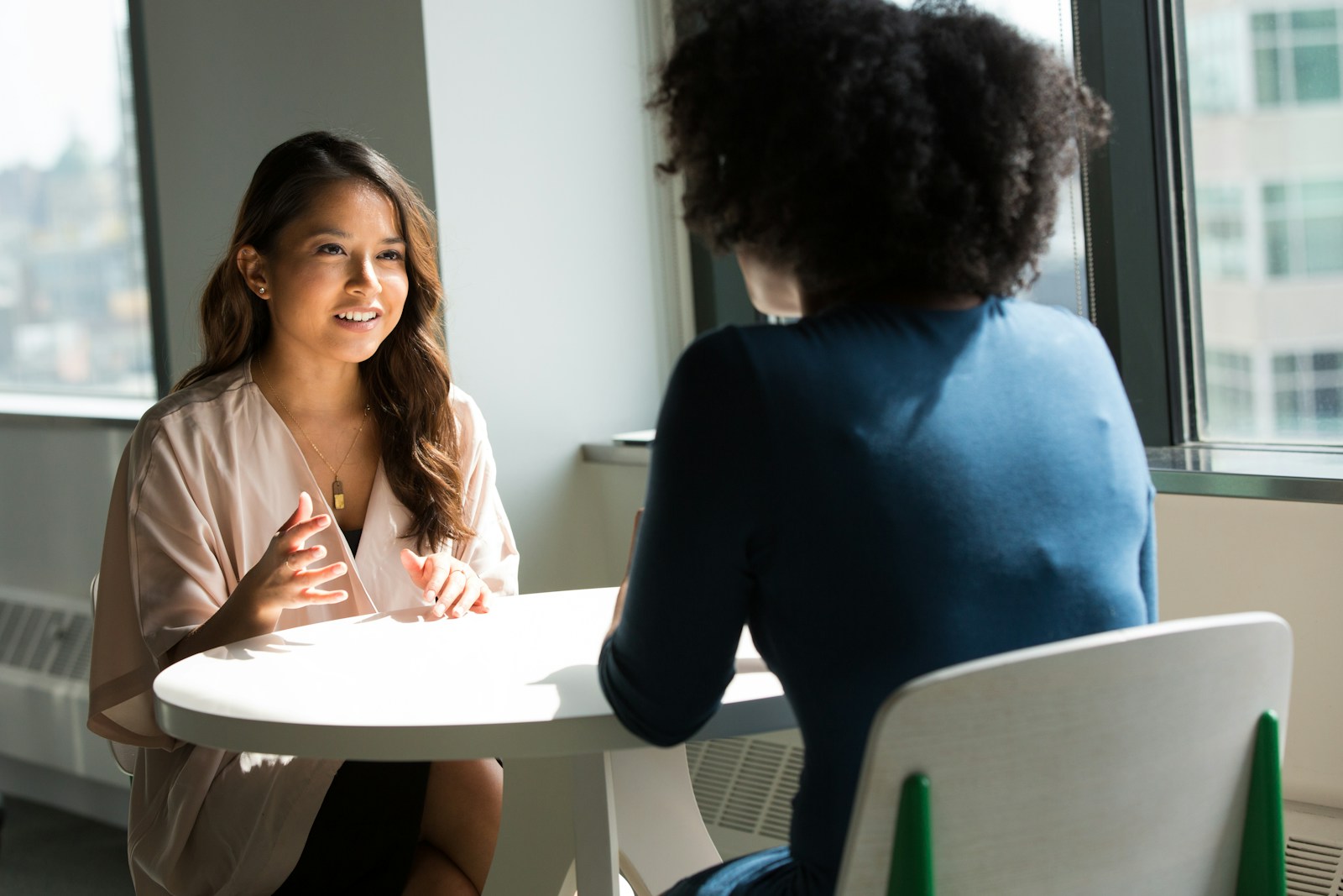 two women sitting on chairs opposite each other at table