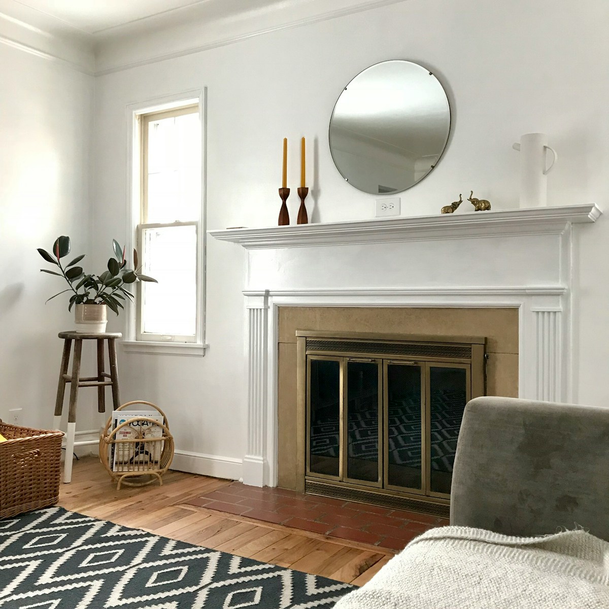 room with white wall and wooden floor and round mirror on the wall