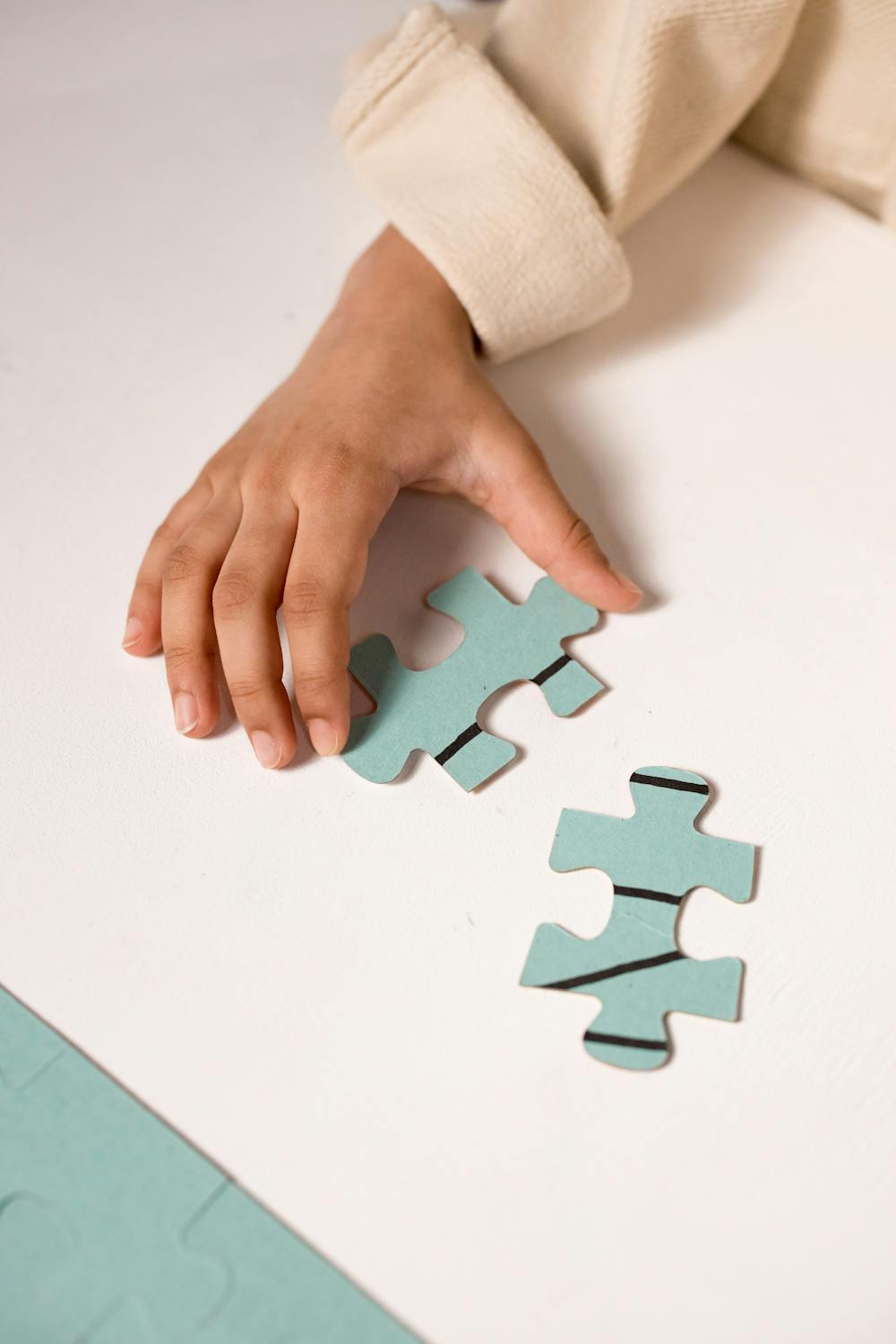 child's hand reaching for jigsaw pieces