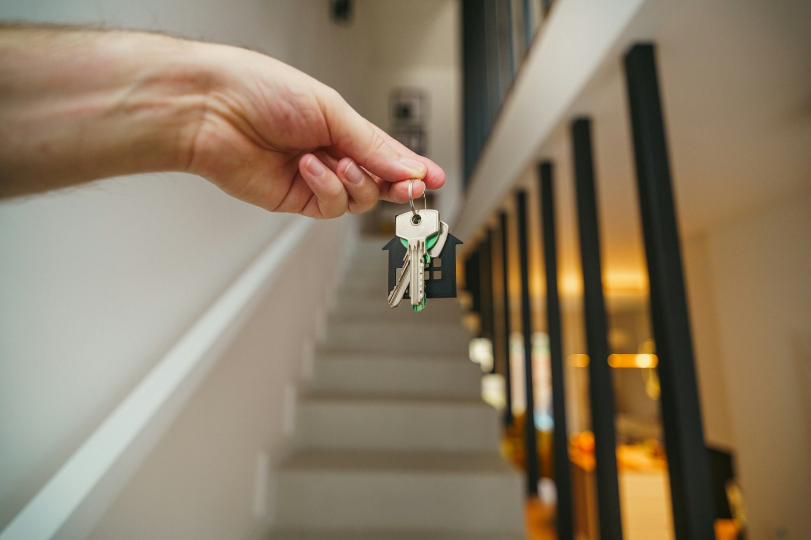 keys being held in front of a staircase.
