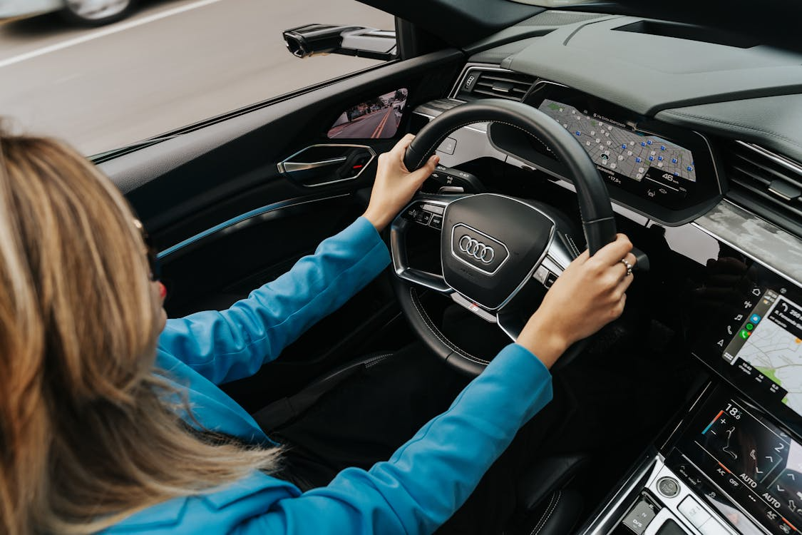 woman wearing blue top with hands on steering wheel in car