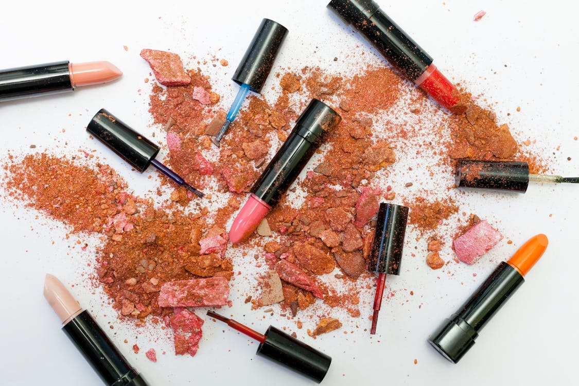 lipsticks and smashed up powedered makeup on white surface