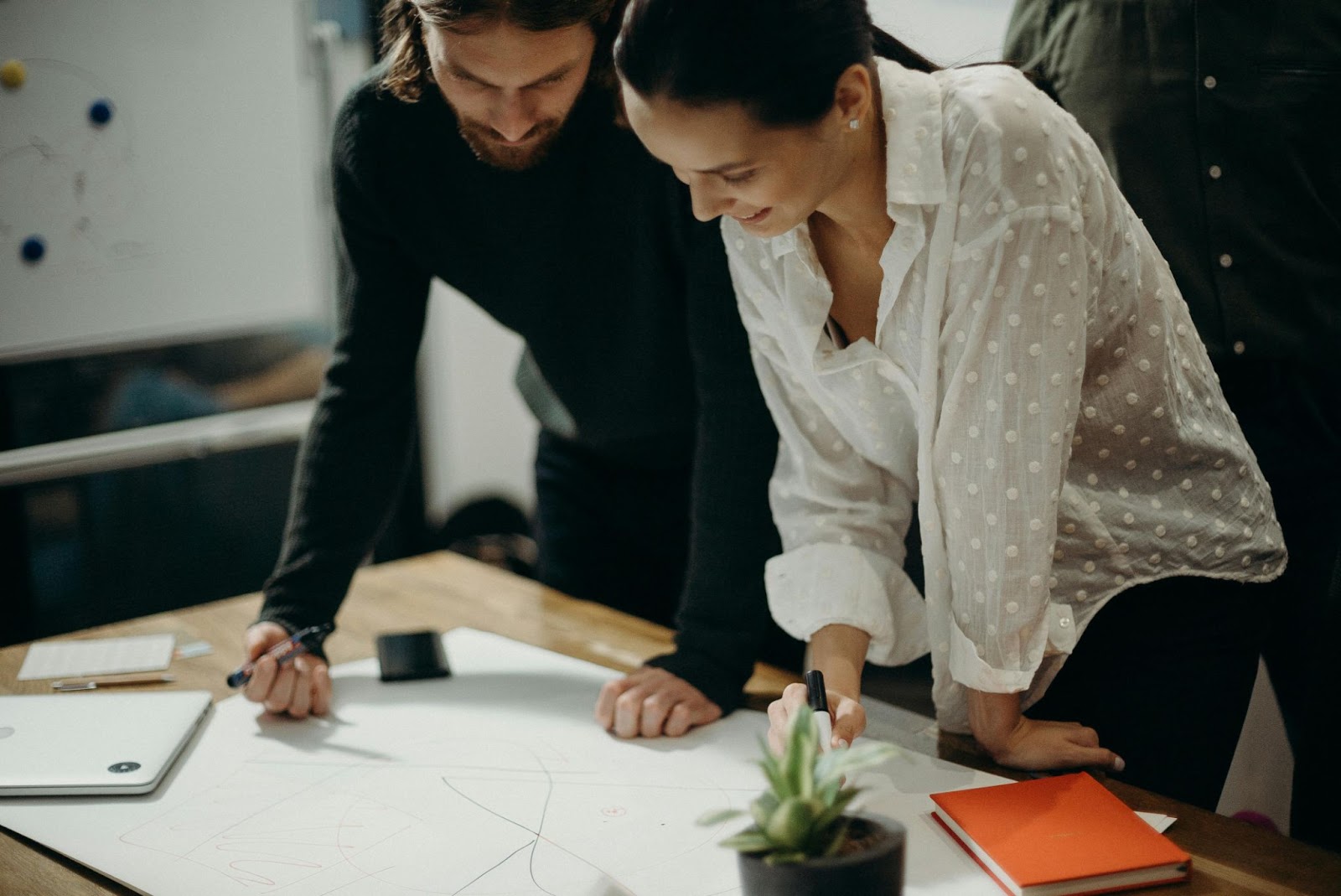 man and woman leaning over design drawing on desk