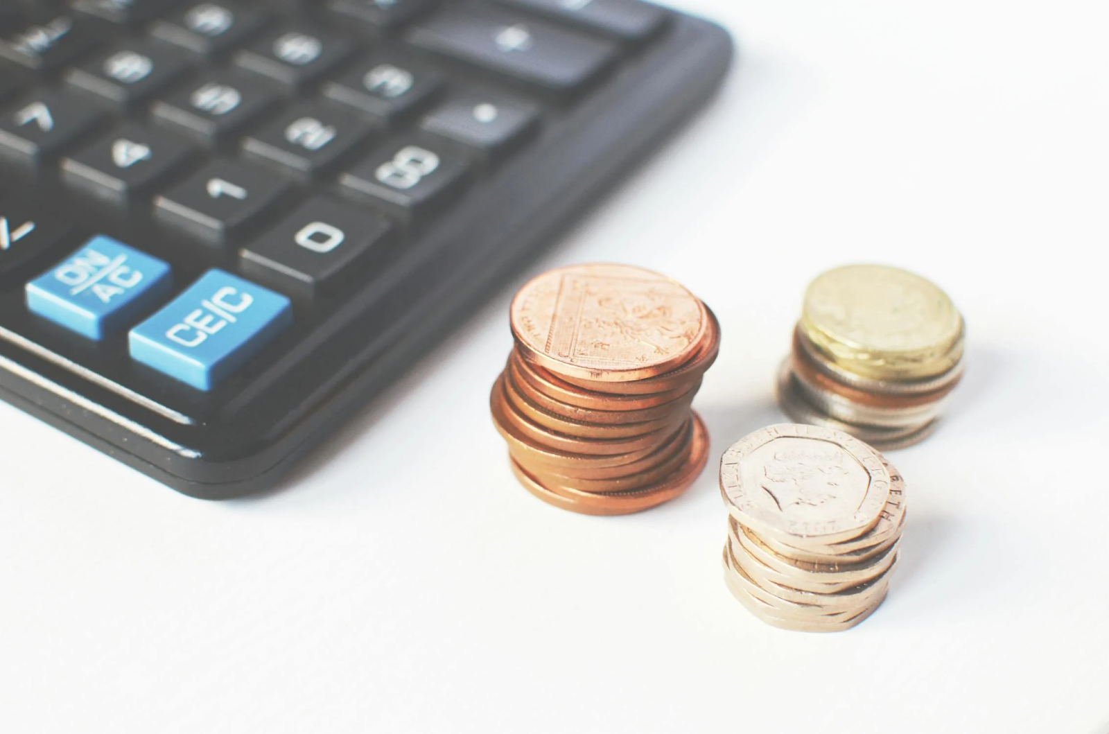 calculator with coins piled up next to it