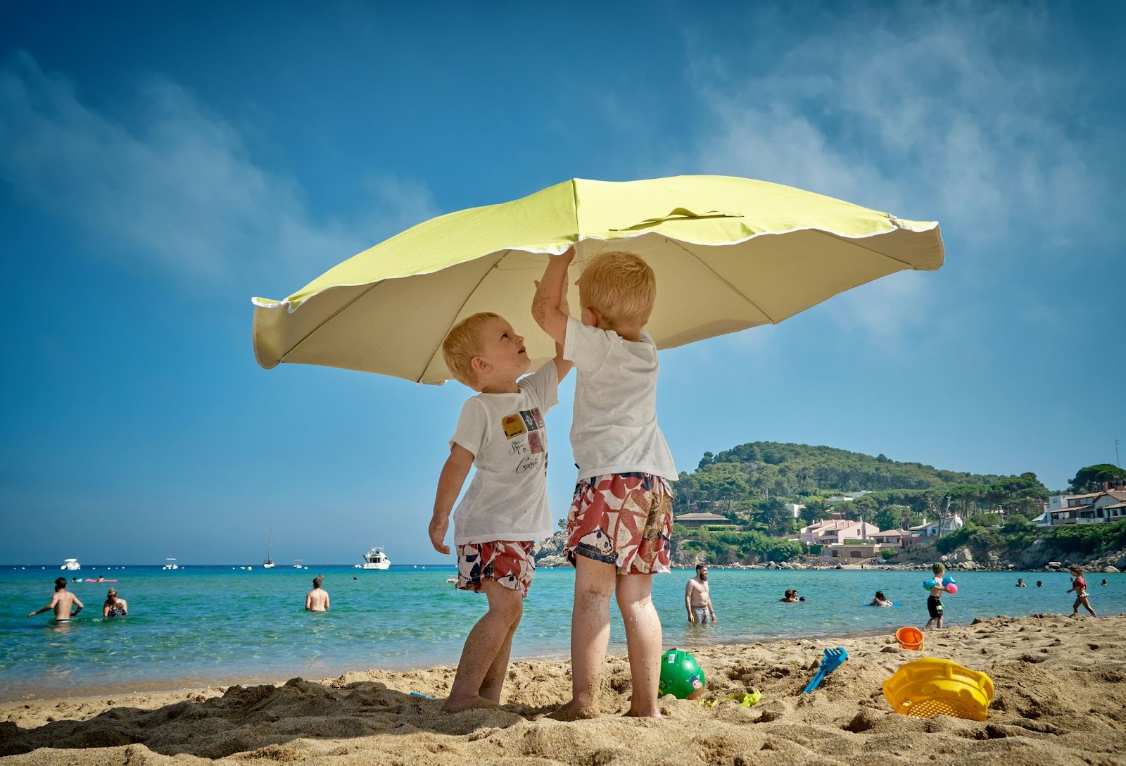 two children under an umbrella on the beach