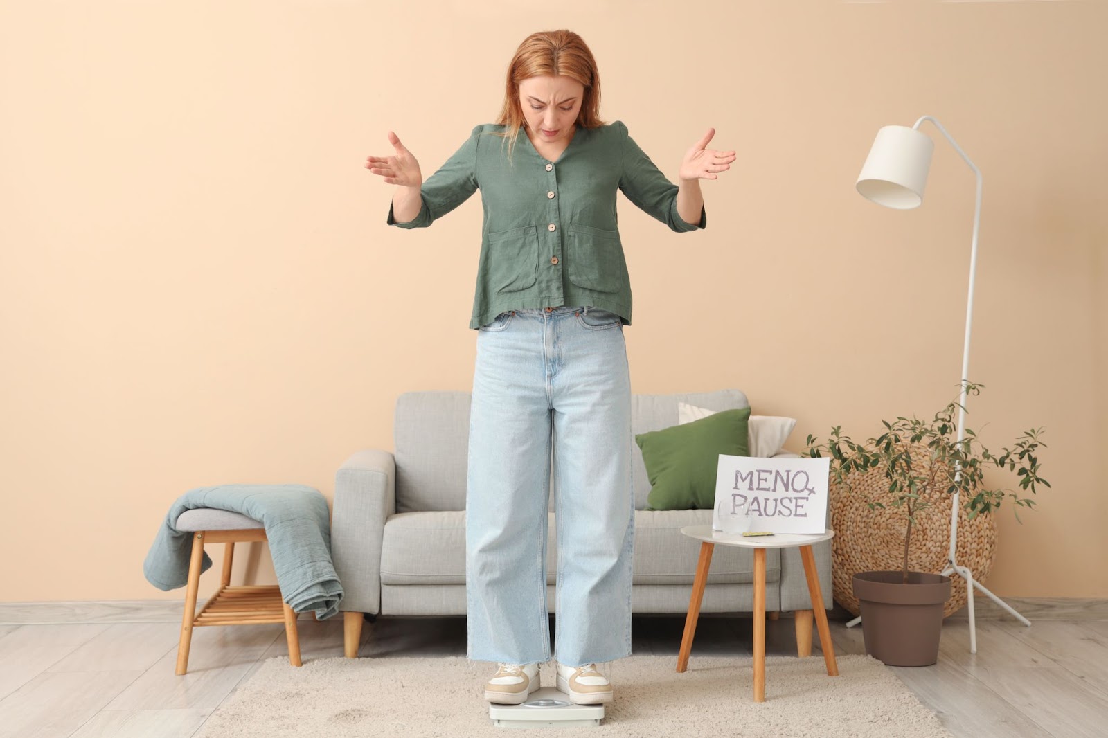 woman standing on scales with arms in the air, and the words 'menopause' on a piece of paper next to her