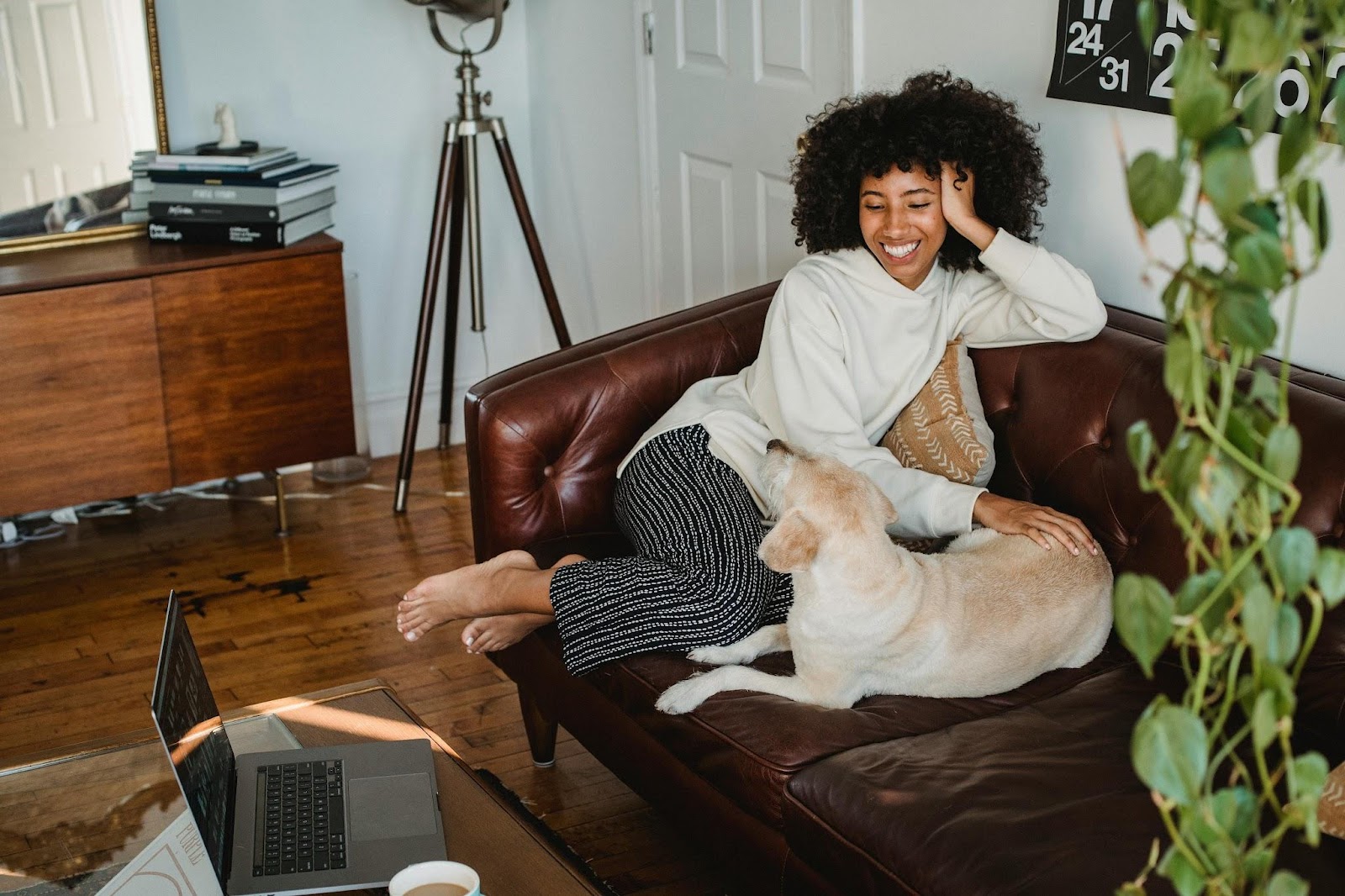 Black woman sitting on sofa with dog and smiling broadly