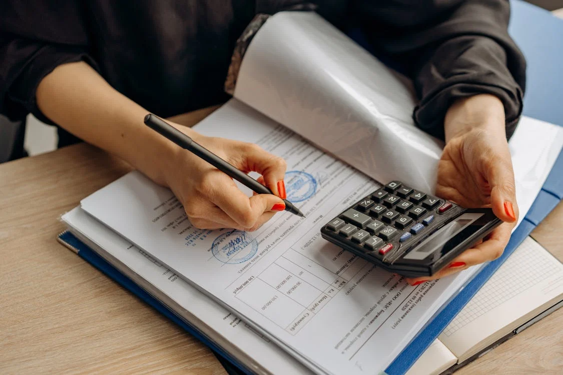 woman's hand wiritng on a form with a calculator in other hand