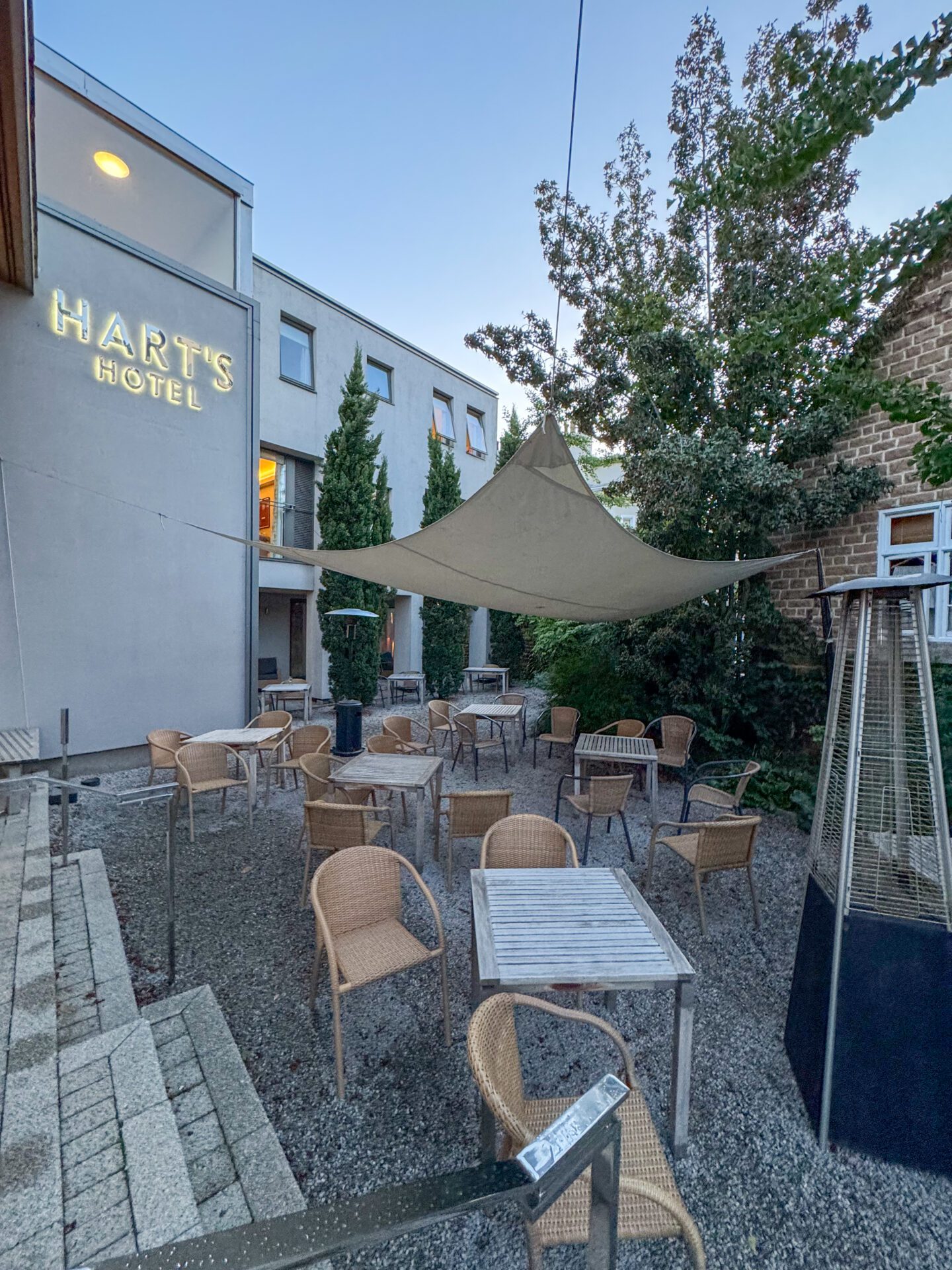 the outside of Hart's hotel in Nottingham, with tables, chairs and an umbrella cover