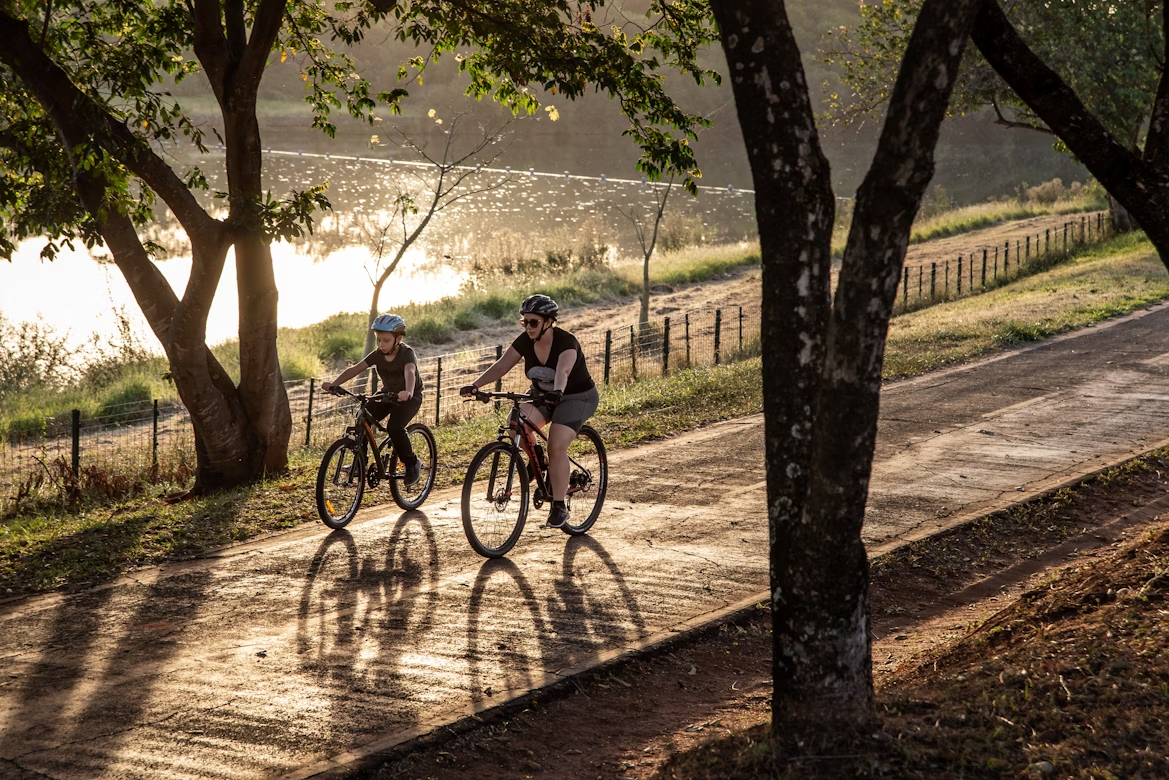 adult and child riding bikes along path next to trees and lake