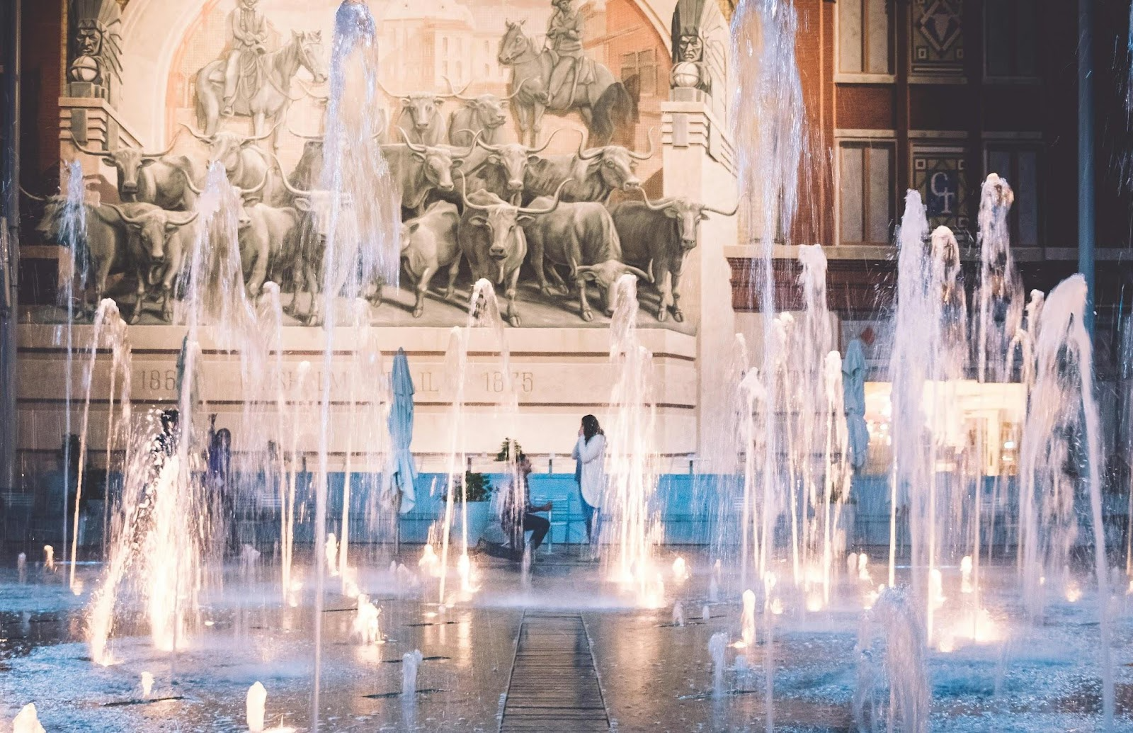 man proposing to woman behind lots of water fountains