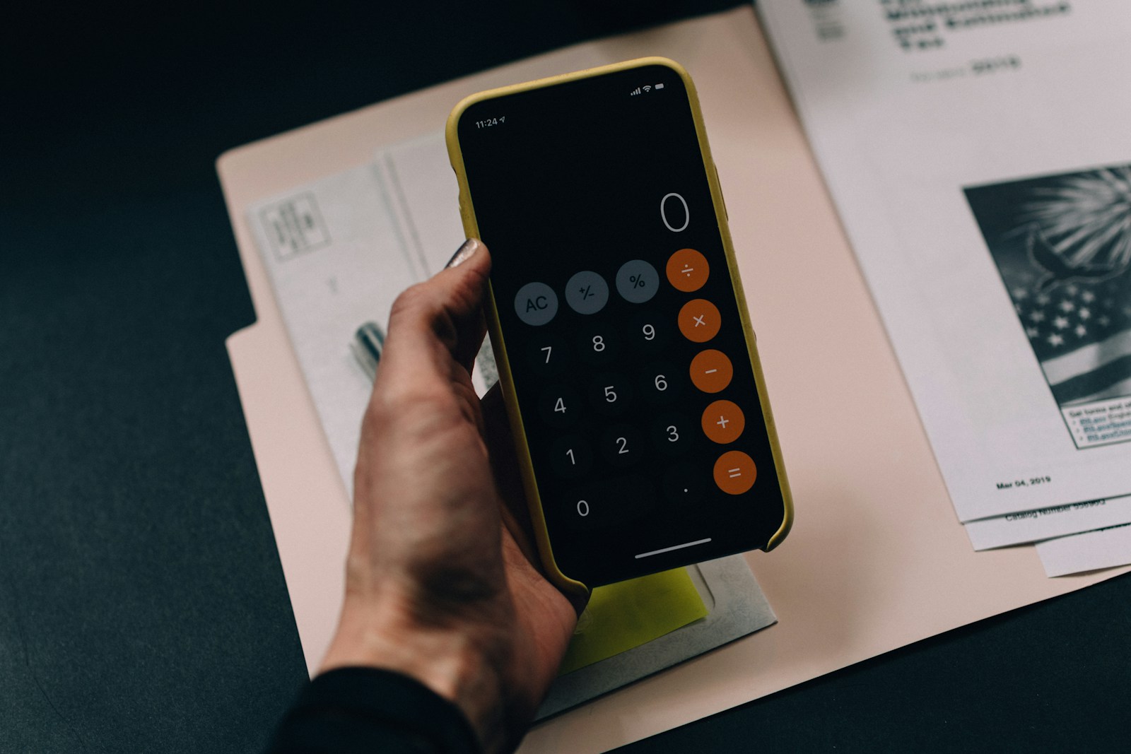 person's hand holding iphone with calculator on the screen