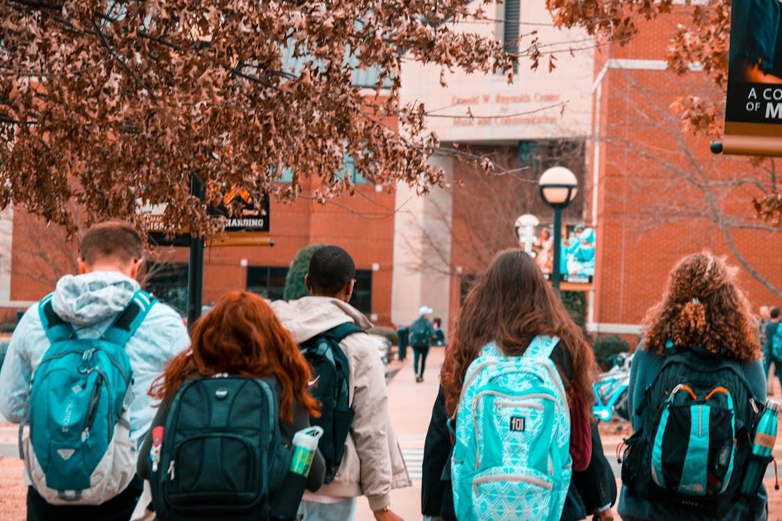 teenagers waring backpacks walking into school
