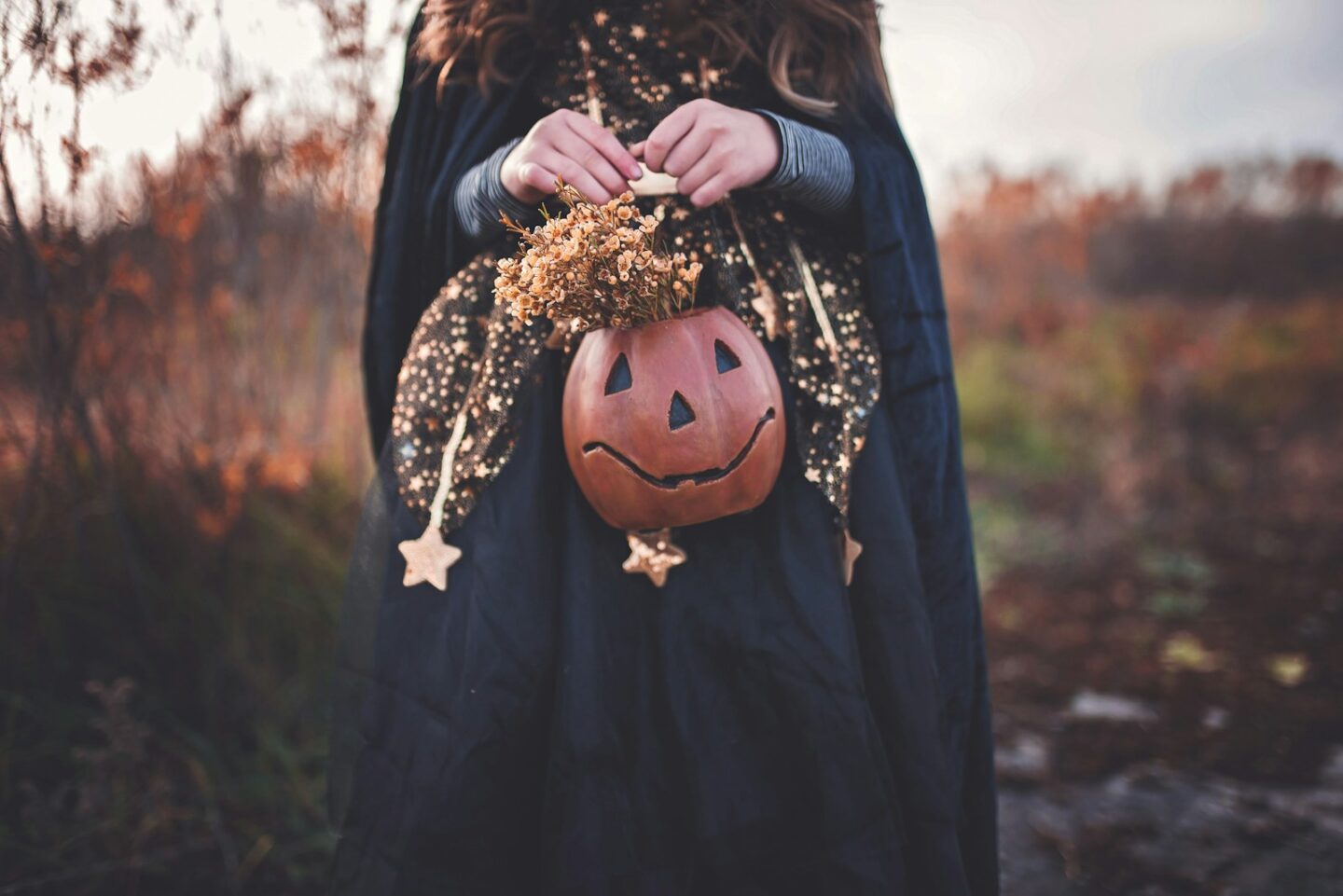 person wearing Halloween costume and holding pumpkin with gold stars