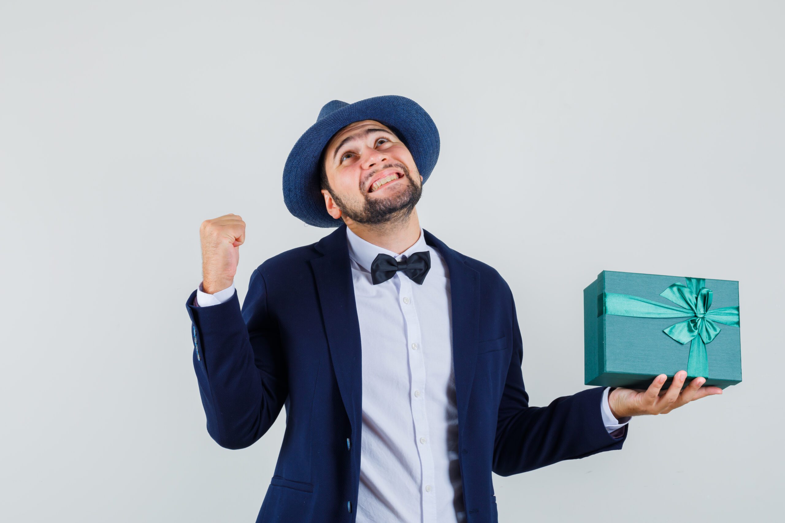 man in suit, bow tie and hat holding present