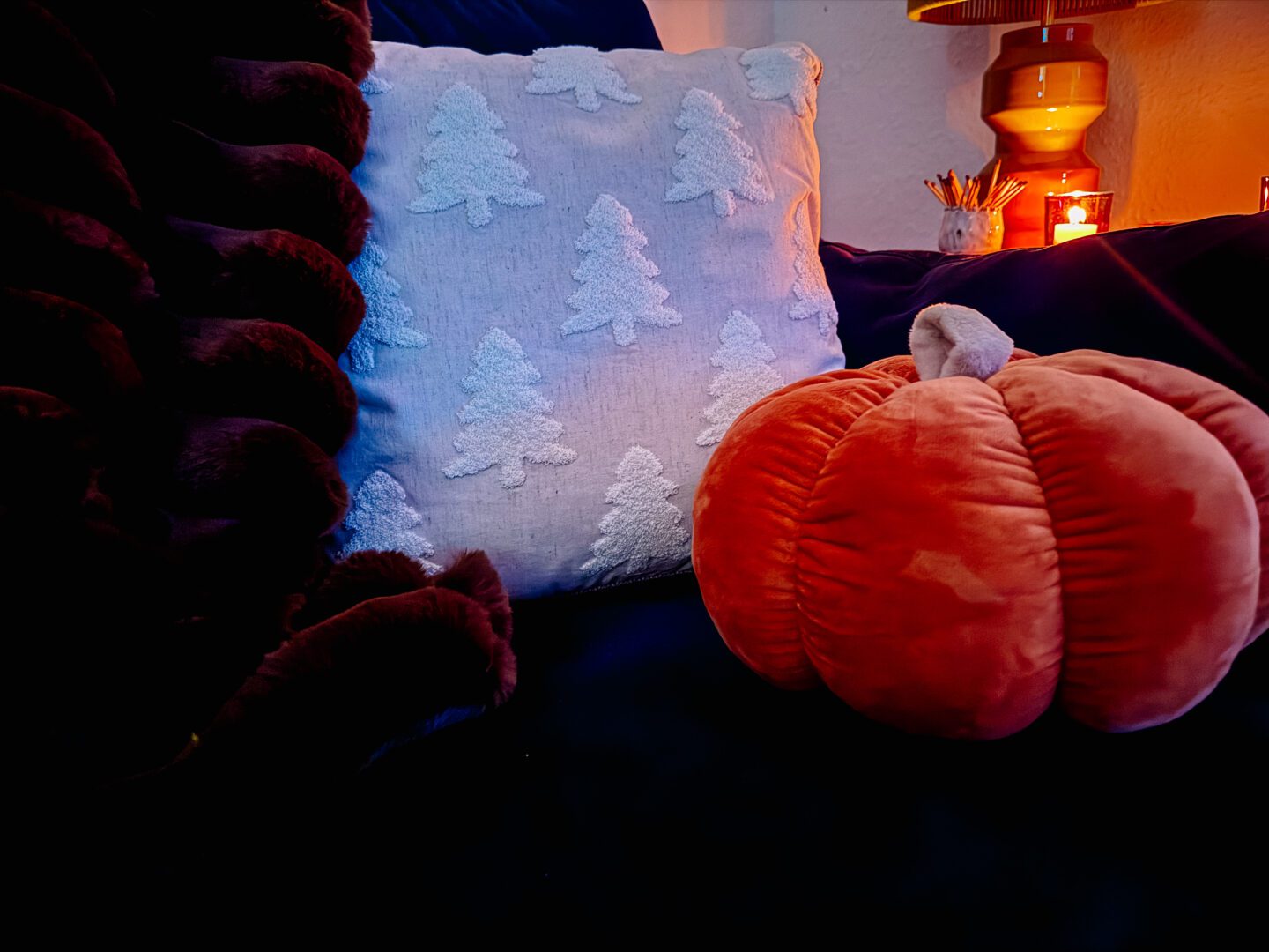 cushion with trees on next to pumpkin cushion and brown throw