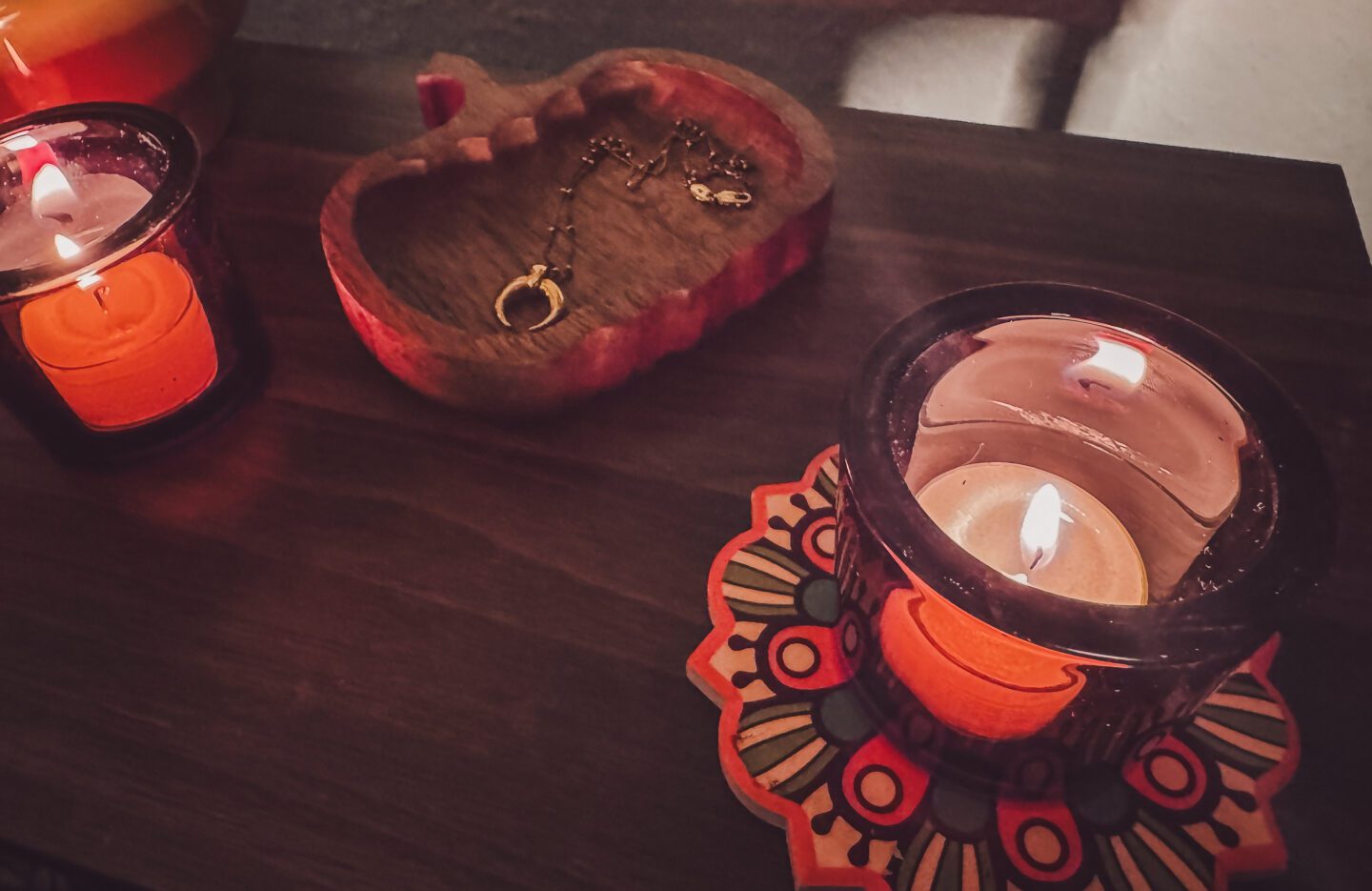  lit tealight on candle holder next to wooden pumpkin dish on coffee table in low lighting
