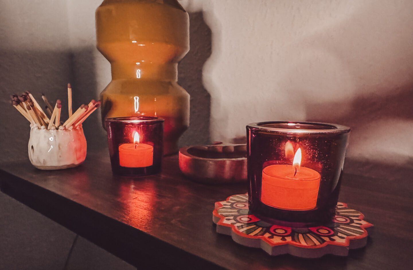 two tealights lit in glass pots on table