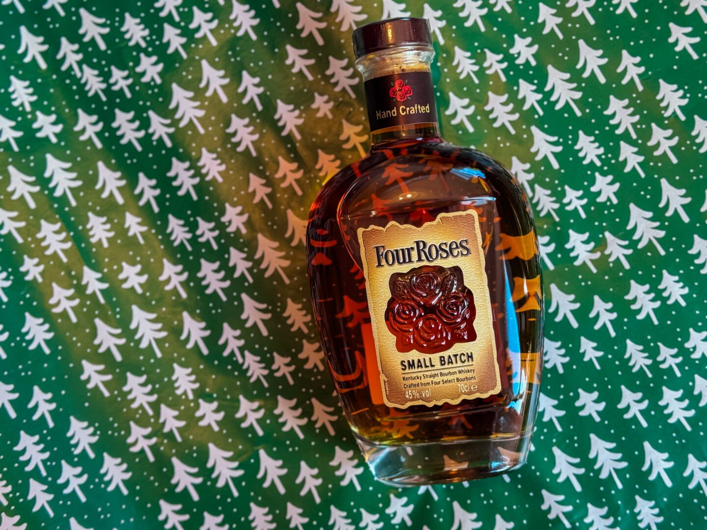 bottole of four roses bourbon on green wrapping paper with white trees
