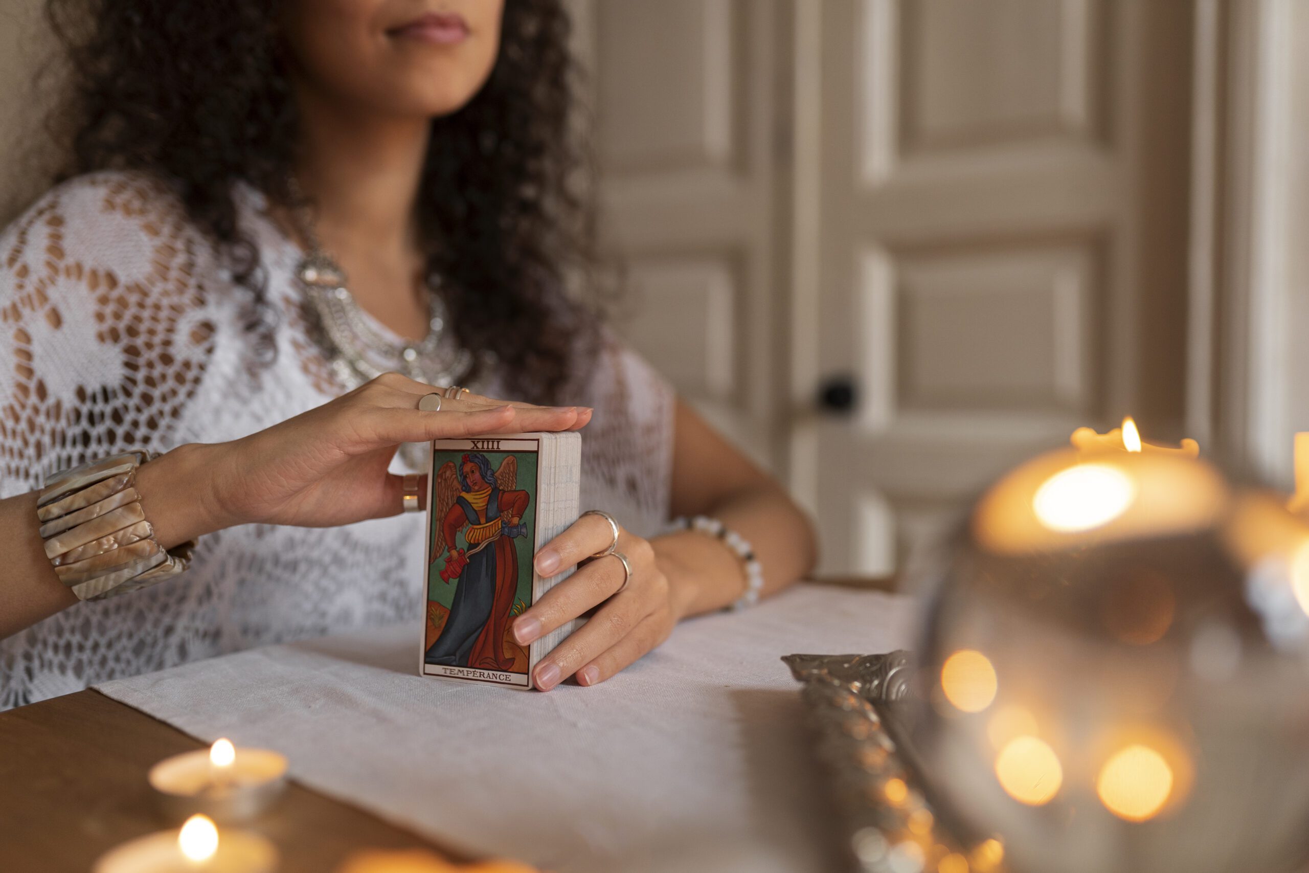 woman sitting at table and holding tarot cards