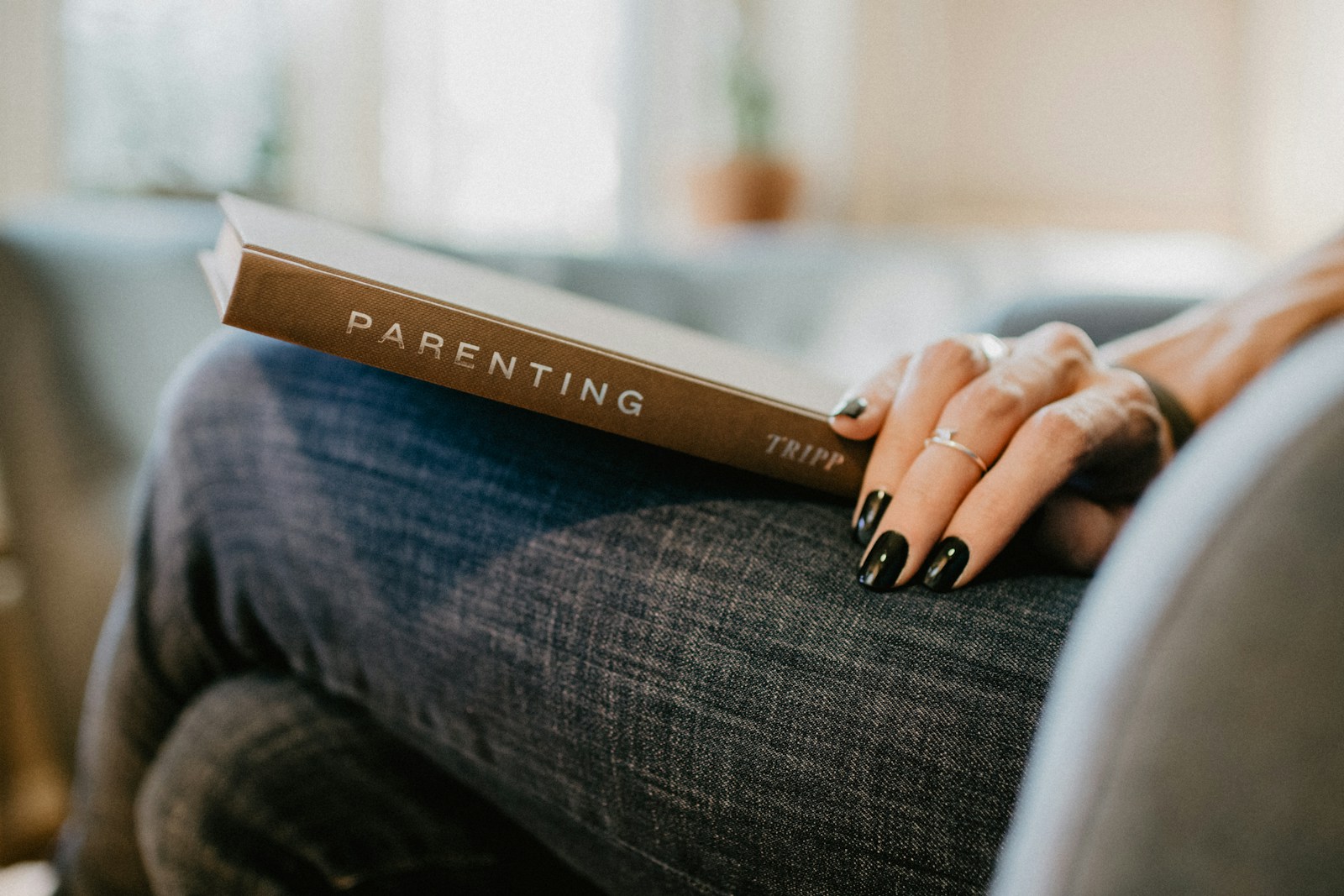 Parenting book on woman's knee with her hand on it