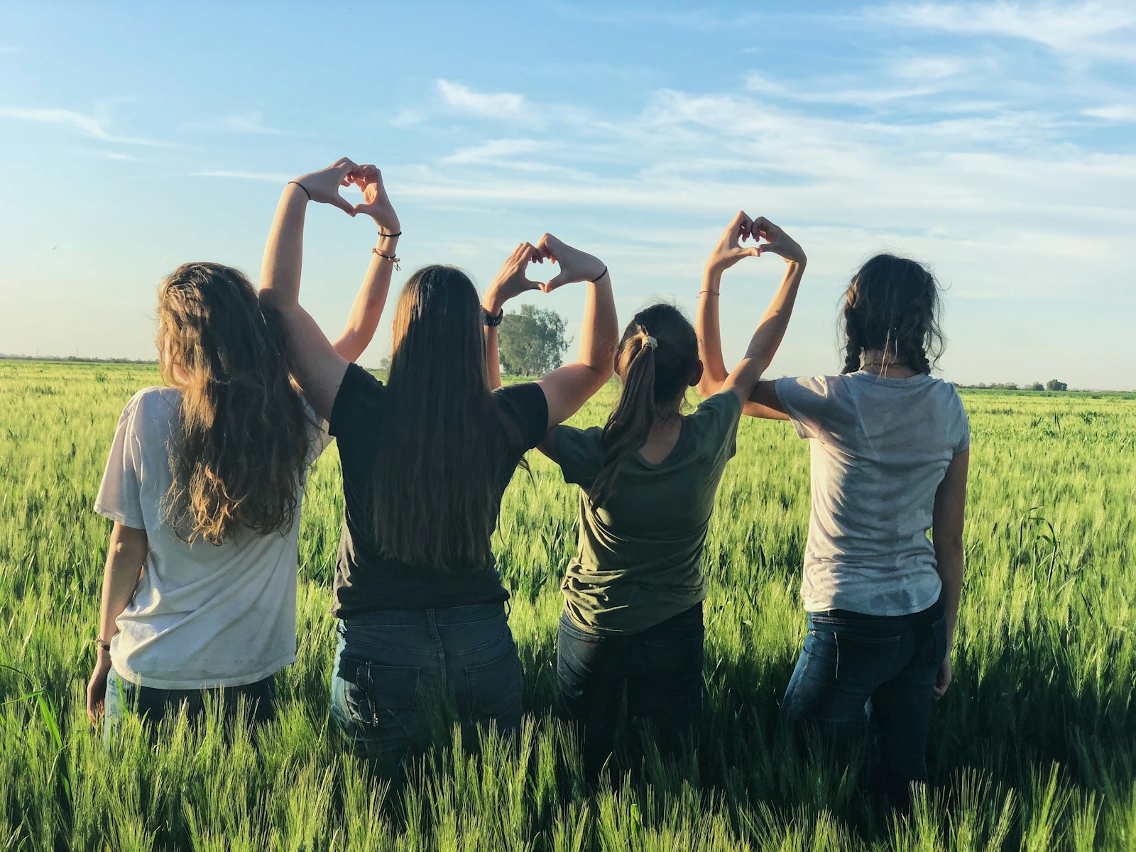group of girls forming heart gestures with hands during daytime