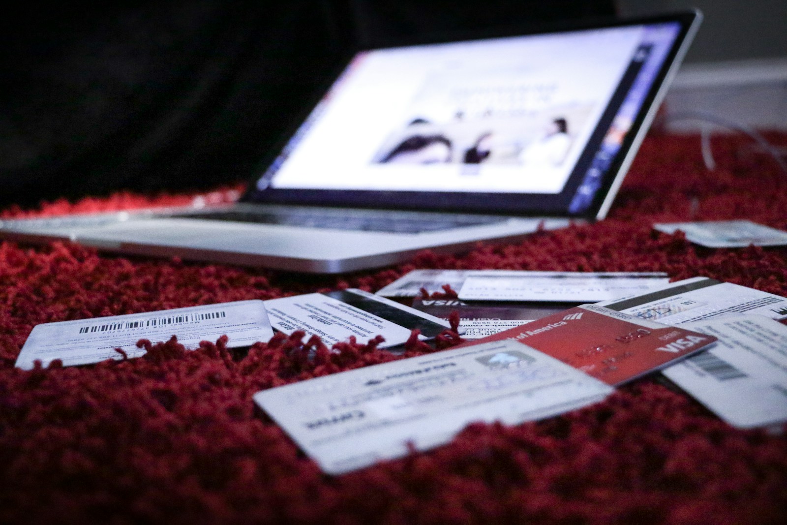 open laptop and bank cards on red rug on floor