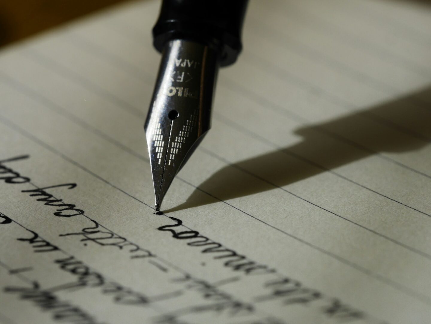 someone writing with fountain pen with black ink on lined paper