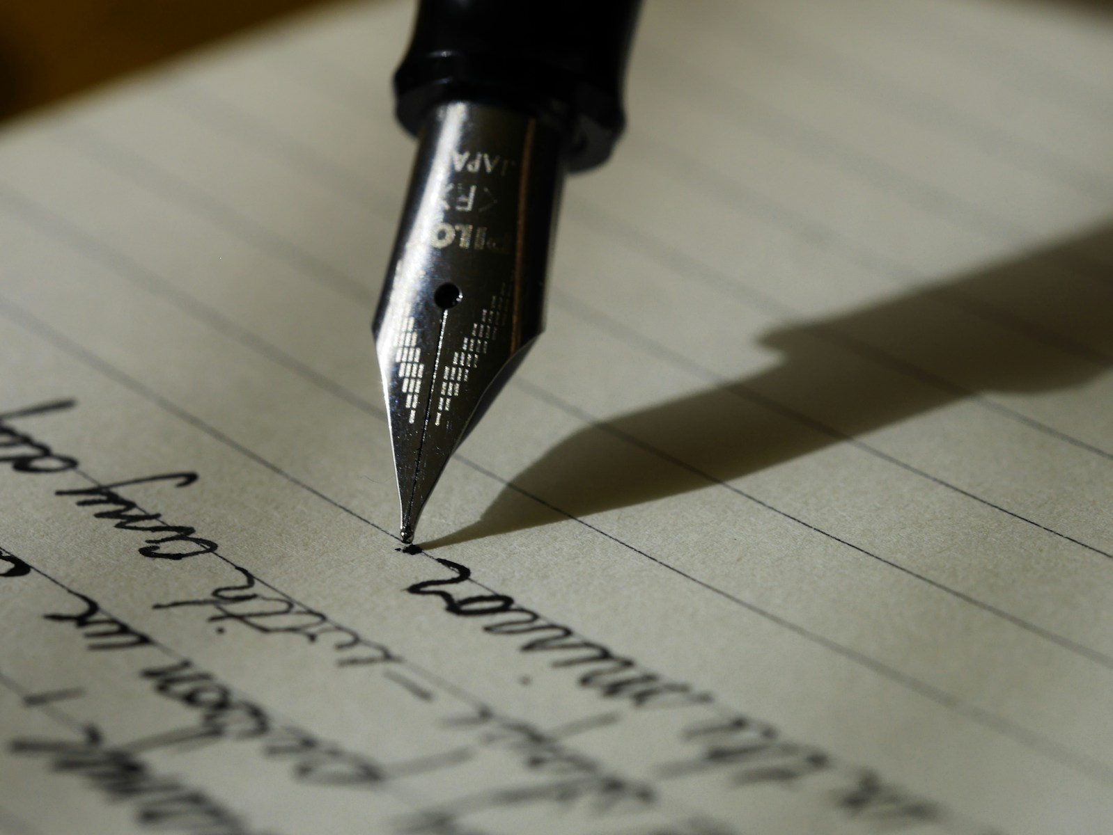 someone writing with fountain pen with black ink on lined paper