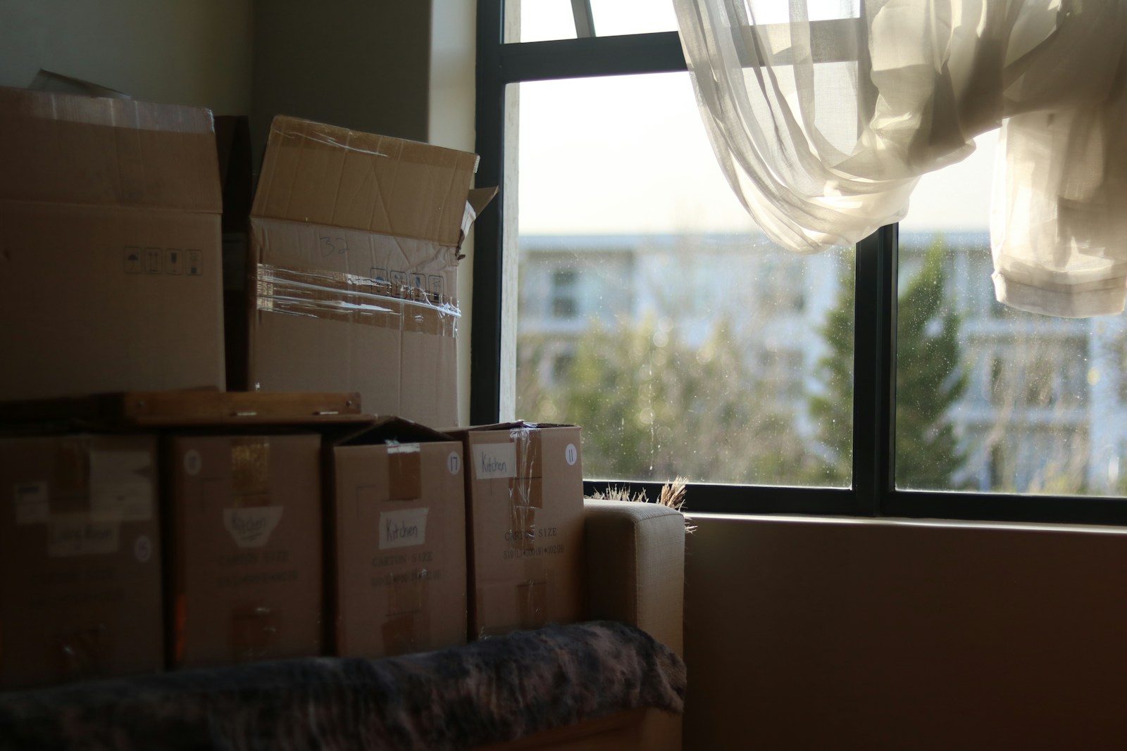 a room with boxes packed and piled up next to a window