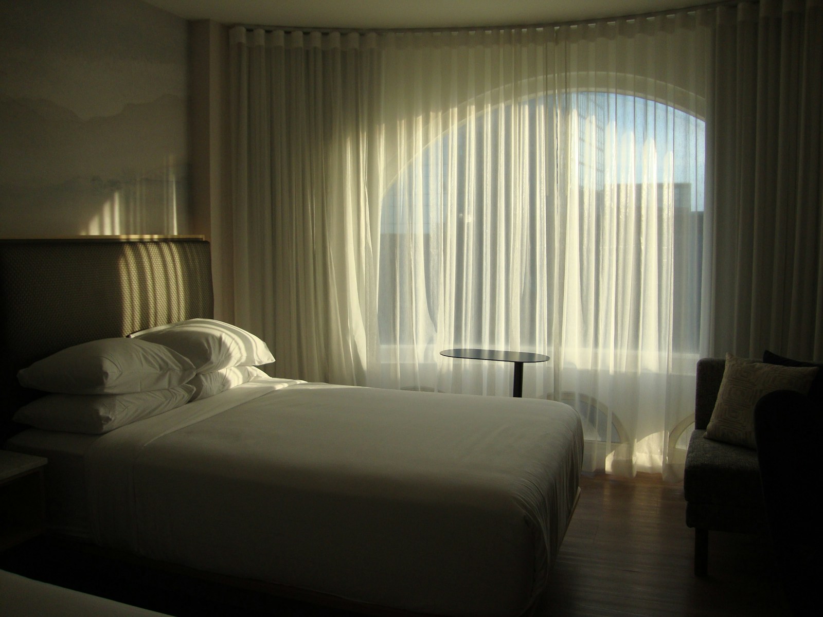 a bed in a bedroom next to a window with curtains at them