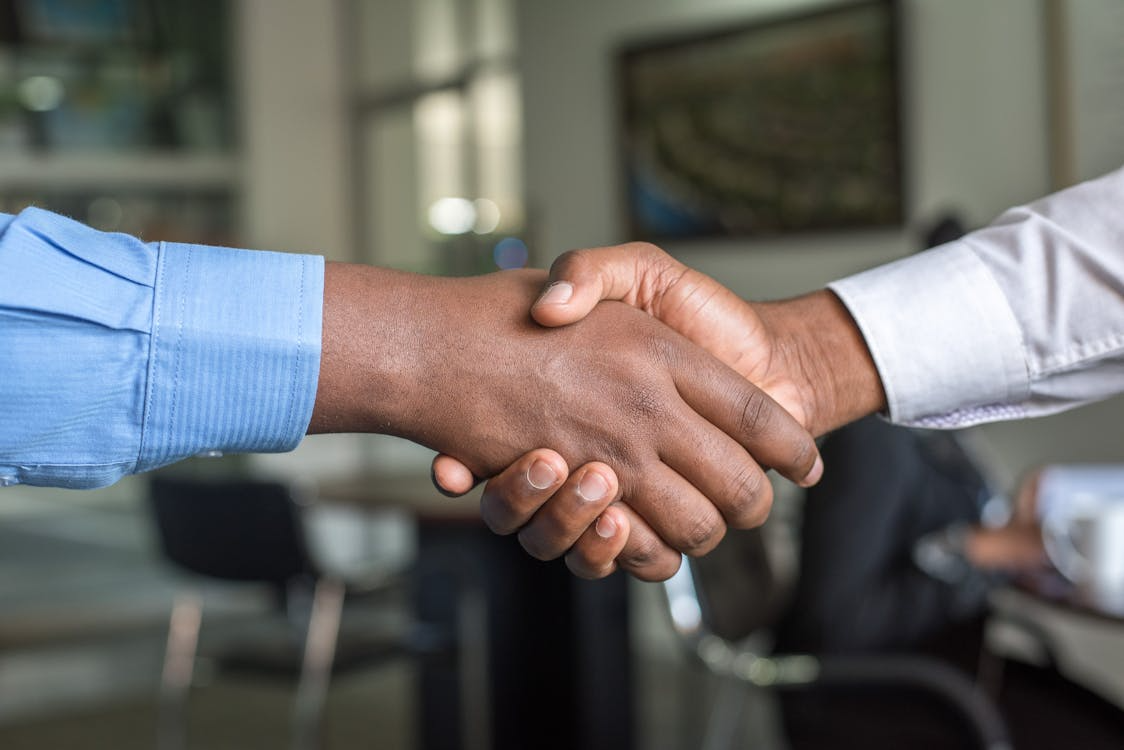 two people wearing shirts shaking hands