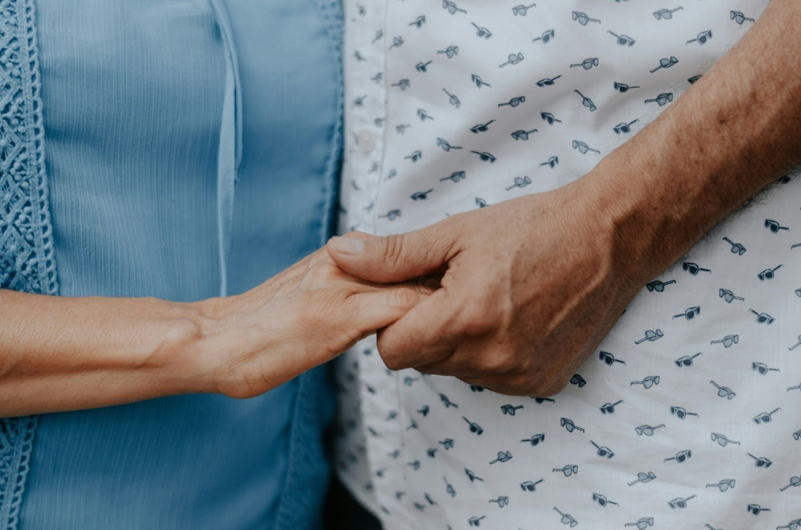 two old people close up holding hands