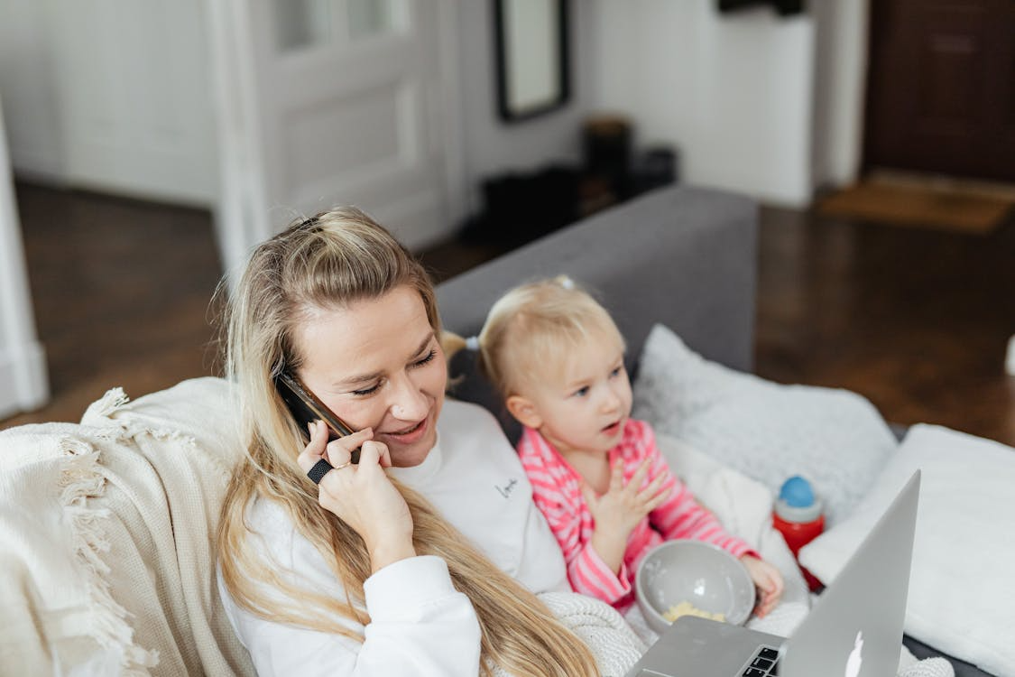 mother on phone, sitting with child on sofa