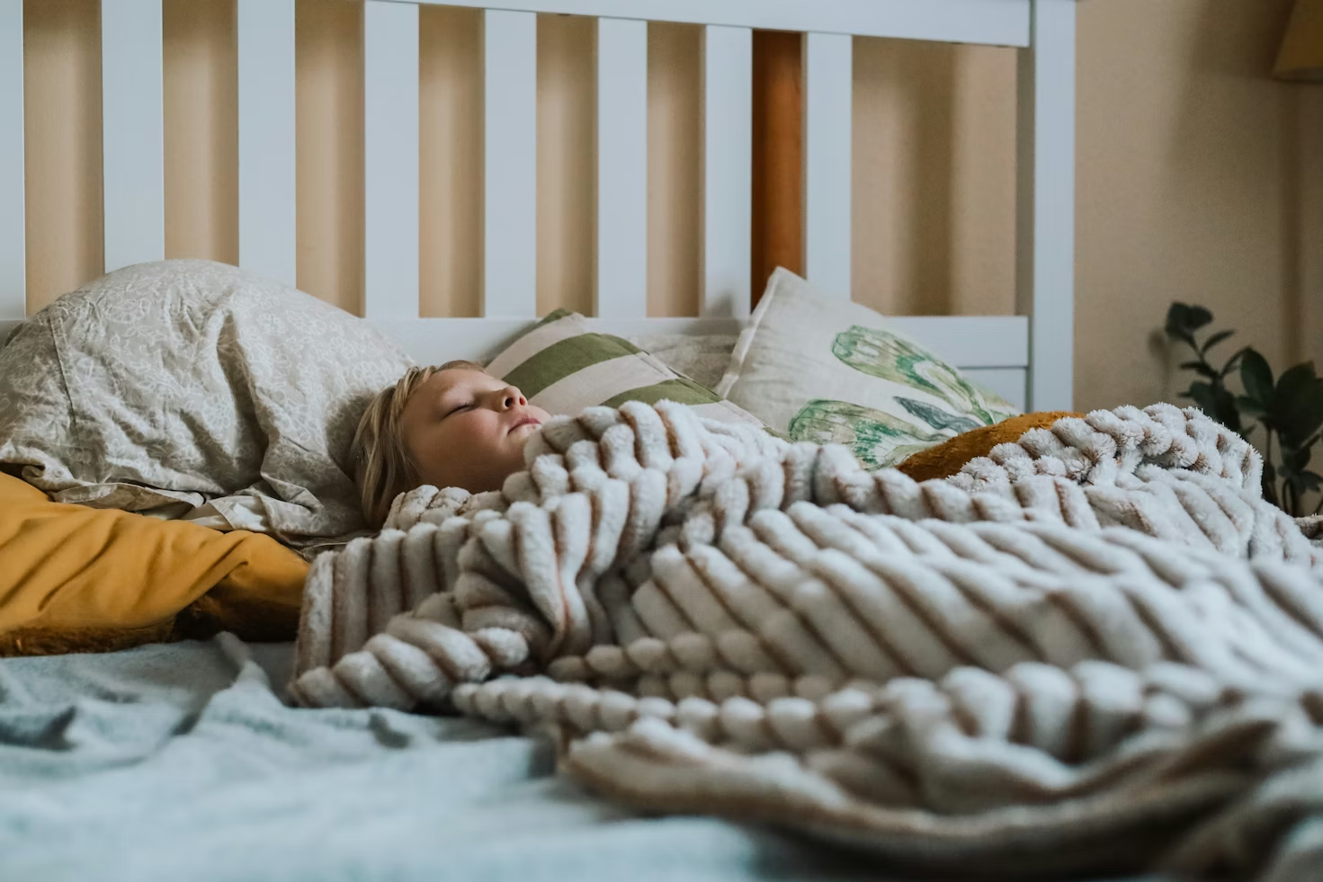 child asleep in bed, covered with a blanket