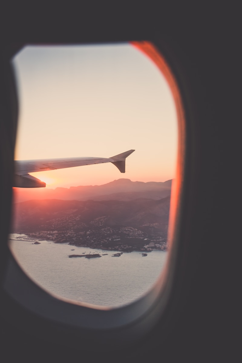 view from aeroplane window of plane wing, land and sea