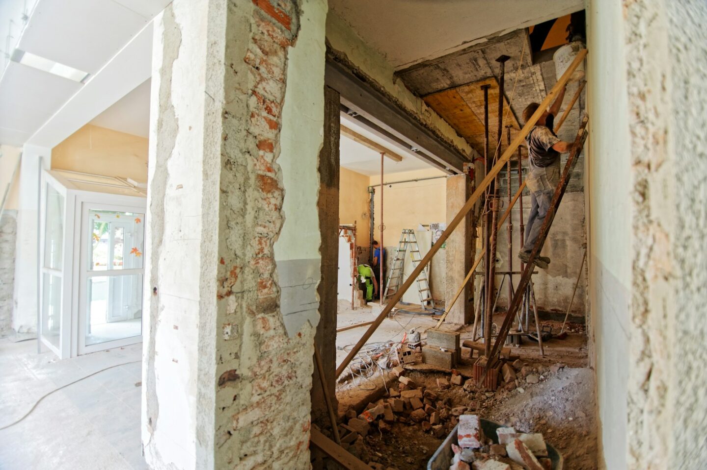 man climbing on ladder inside room in house that is being renovated.